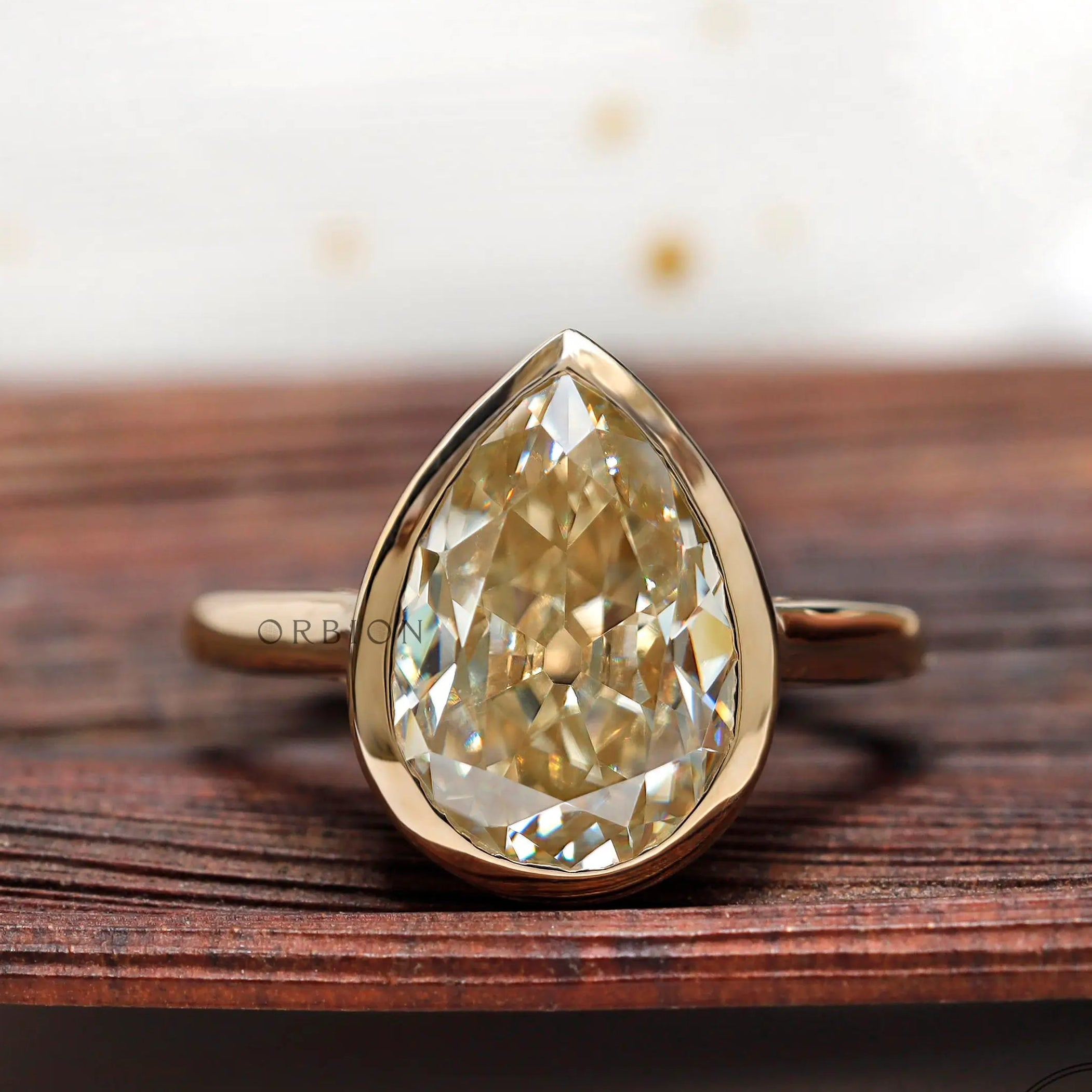 Pear old mine cut moissanite bezel set solitaire ring in yellow gold front view