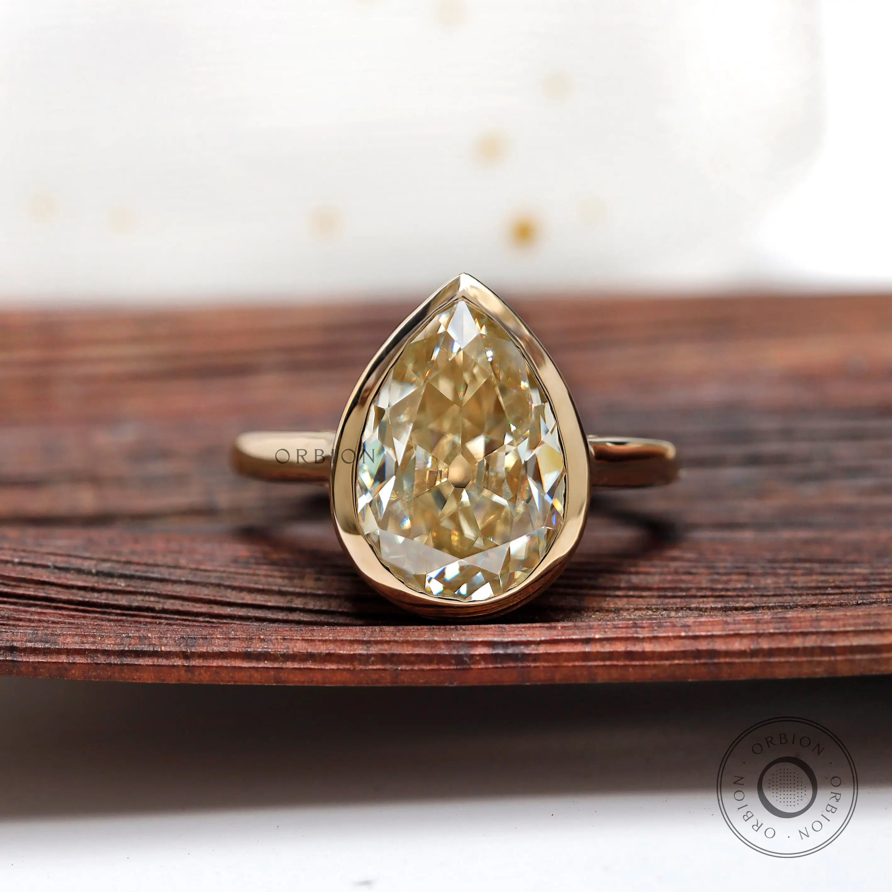 Pear old mine cut moissanite bezel set solitaire ring in yellow gold front view