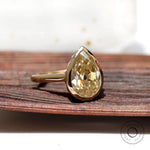 Close view of gold bezel setting holding pear moissanite