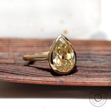 Close view of gold bezel setting holding pear moissanite
