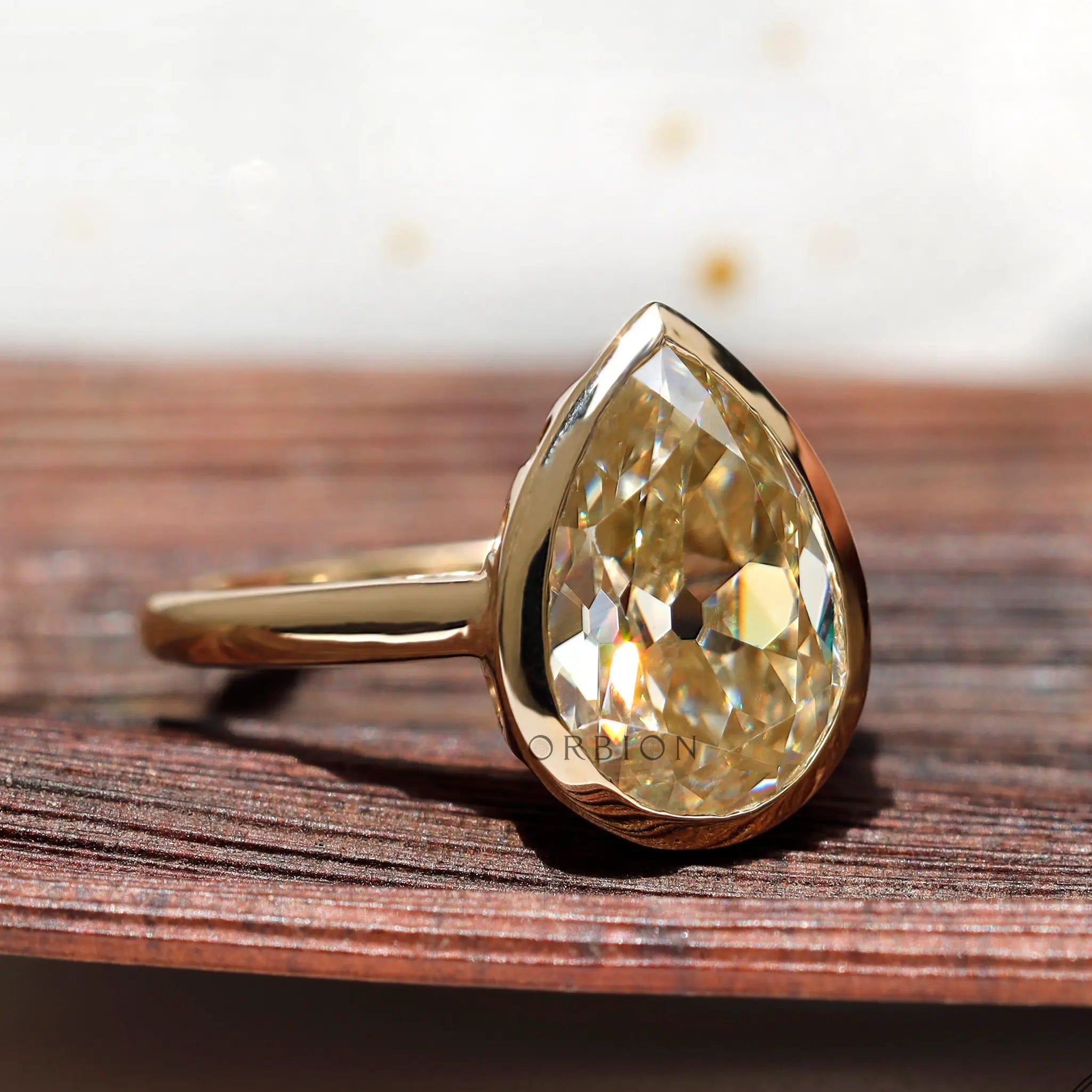 Close view of gold bezel setting holding pear moissanite