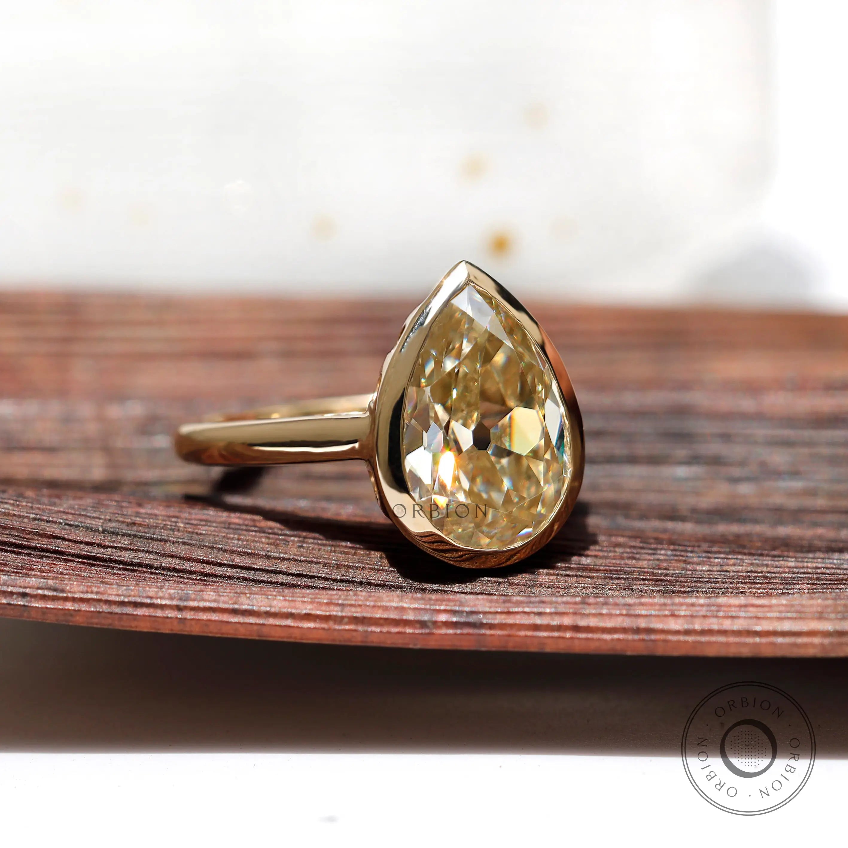 Close view of gold bezel setting holding pear moissanite