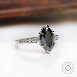 Front centered view of deep green marquise moissanite ring with round side stones