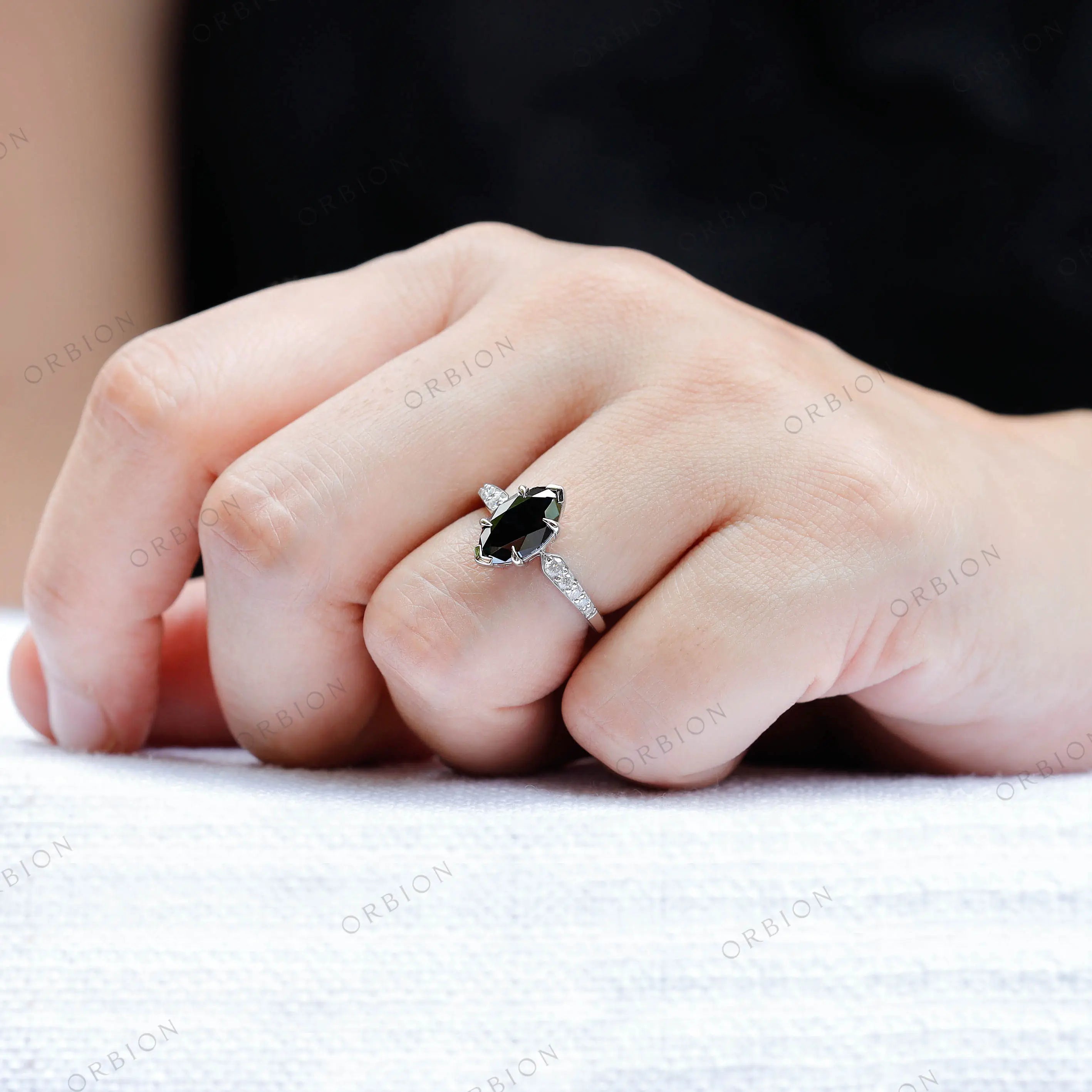 Marquise green moissanite engagement ring on finger close up