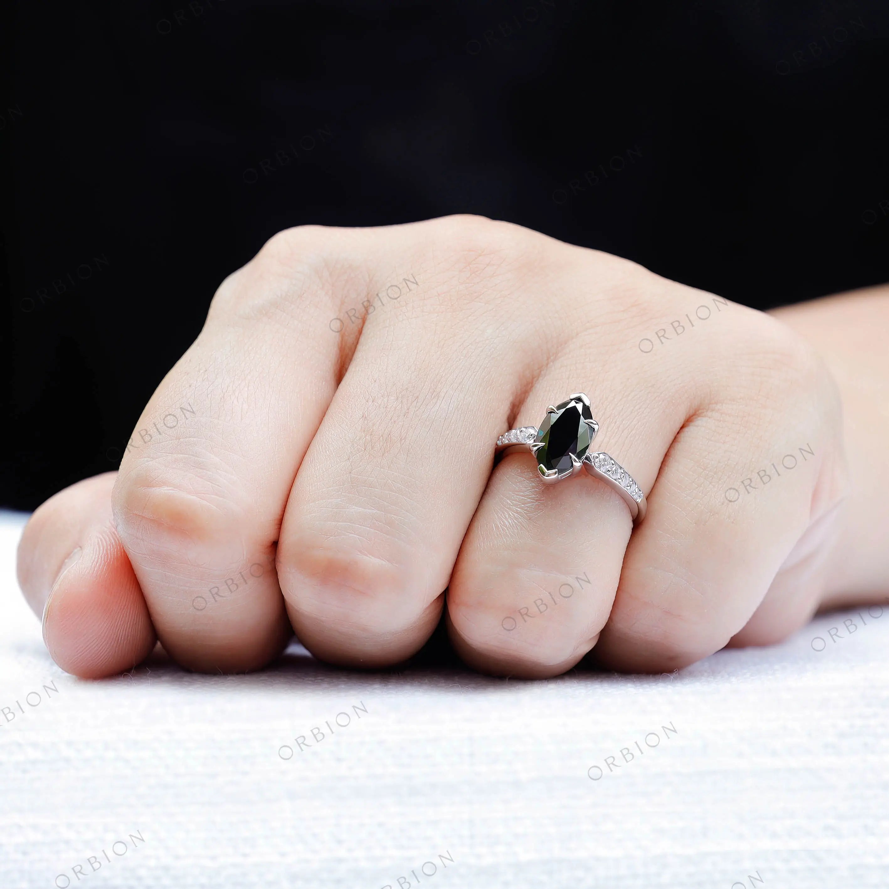 Hand shot of deep green Old Mine Cut moissanite ring with accent stones