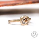 Angled side view of the solitaire cushion cut dark champagne moissanite engagement ring