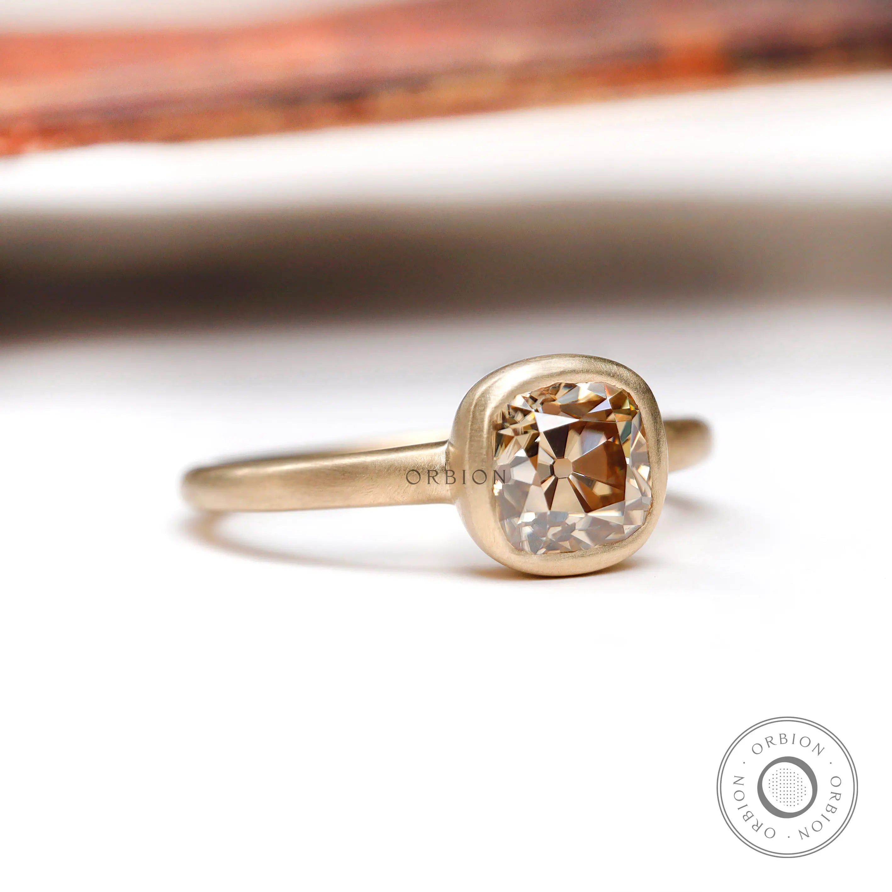 Angled side view of the solitaire cushion cut dark champagne moissanite engagement ring