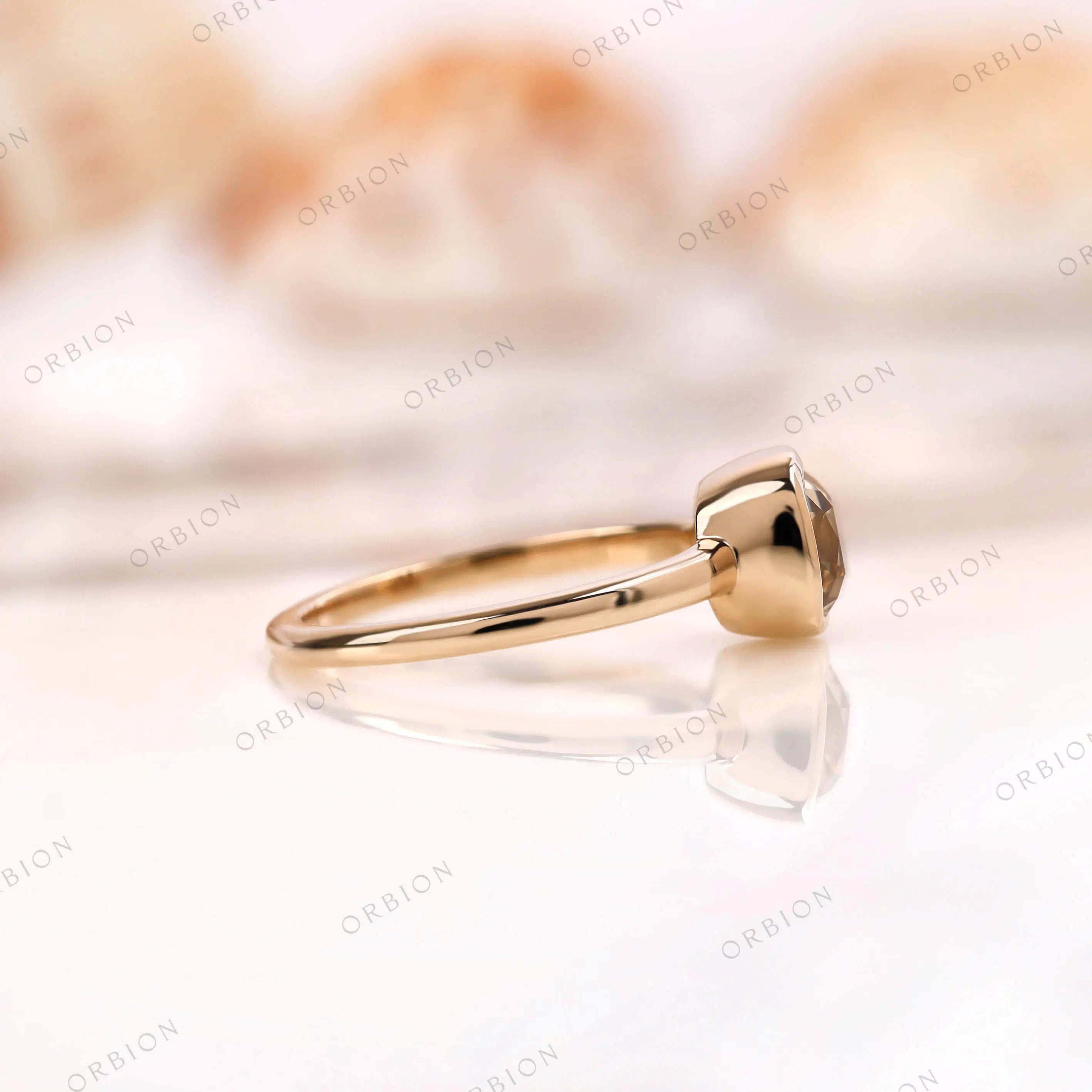 Side view of Moissanite Light Champagne Old Mine Cut bezel set solitaire ring in 10K yellow gold setting