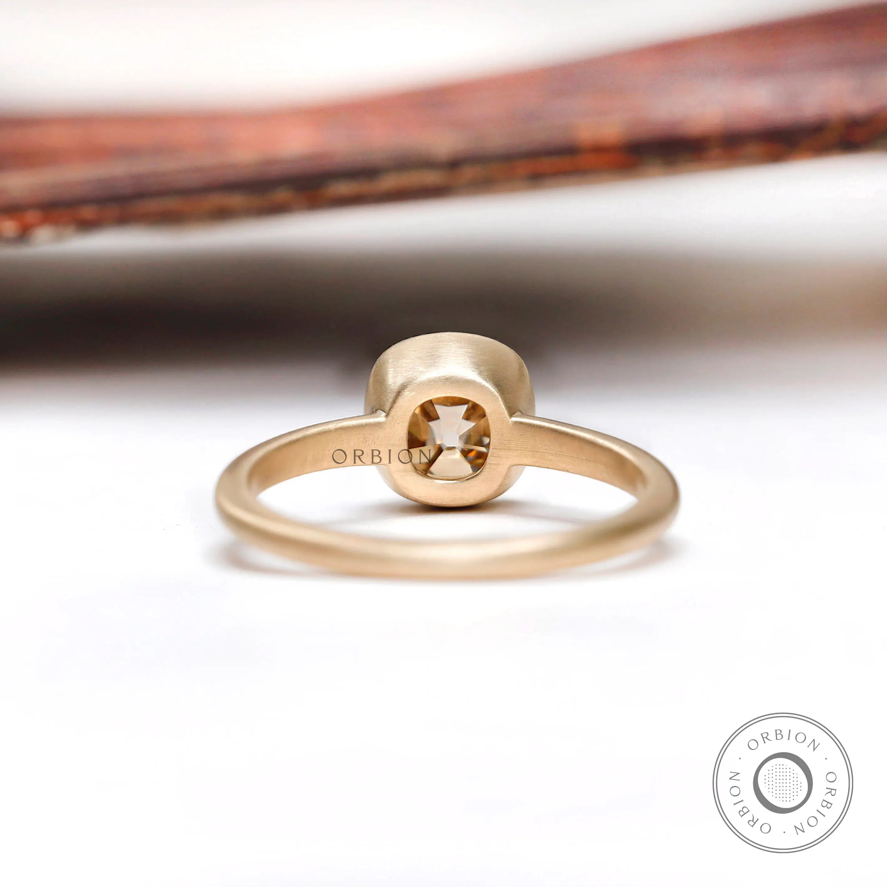 Back view of the solitaire cushion cut dark champagne moissanite bezel set engagement ring in matte
