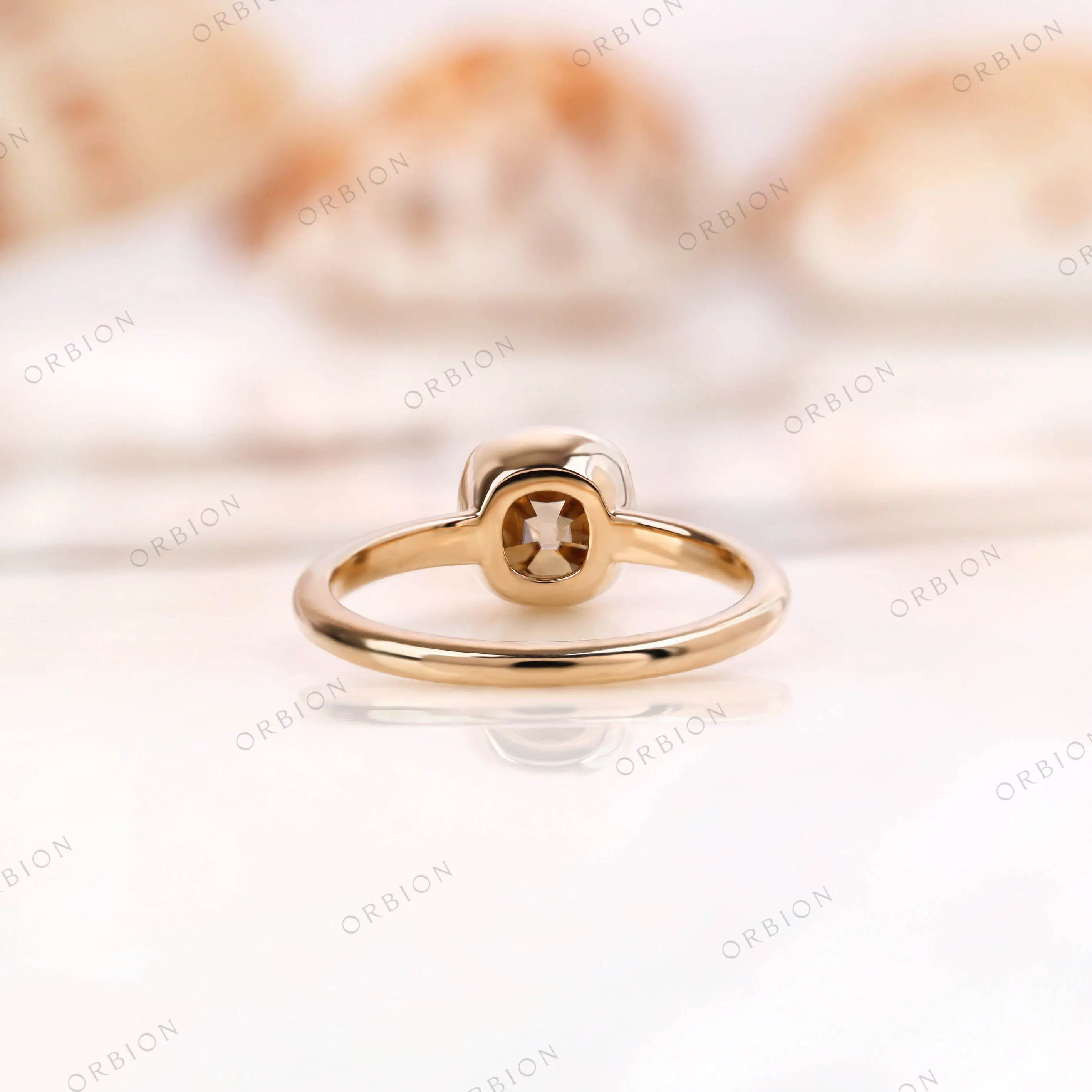 Back view of Moissanite Light Champagne Old Mine Cut bezel set solitaire ring in 10K yellow gold