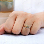 Close-up of Moissanite Light Champagne Old Mine Cut bezel set solitaire ring in 10K yellow gold worn on hand