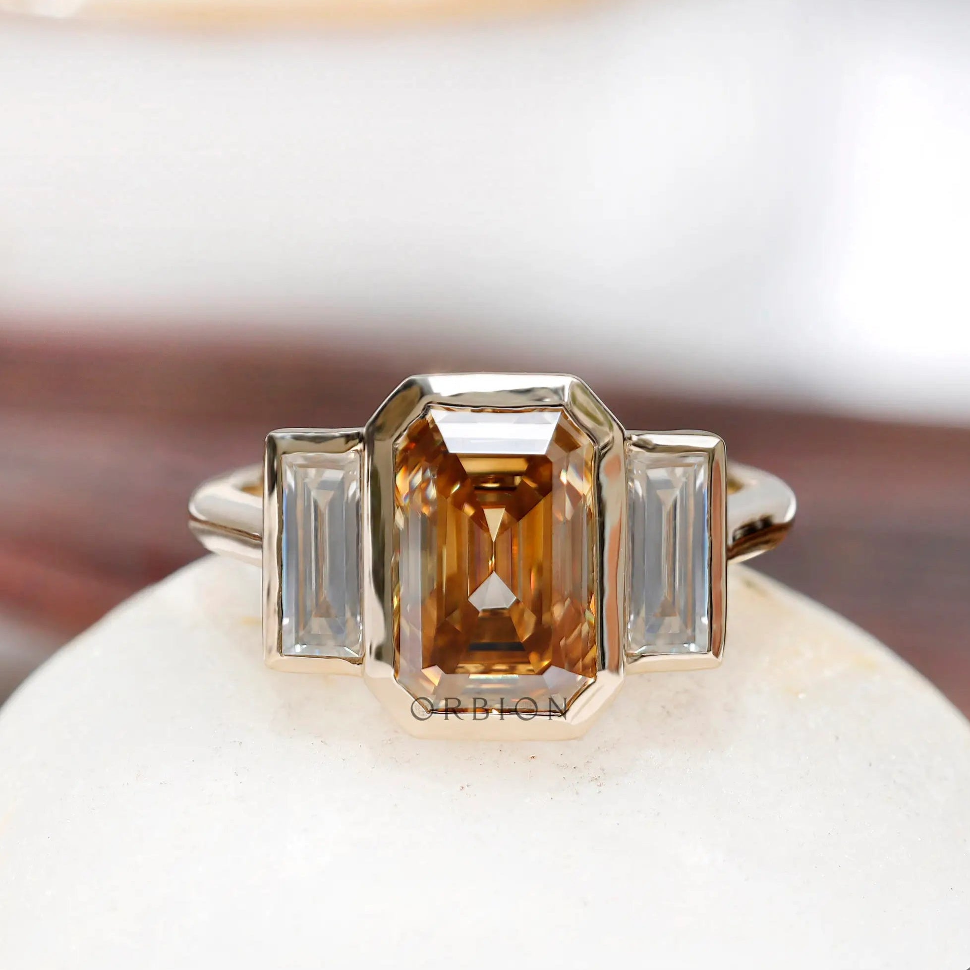 Dark champagne emerald cut moissanite three stone bezel set ring in 14K yellow gold