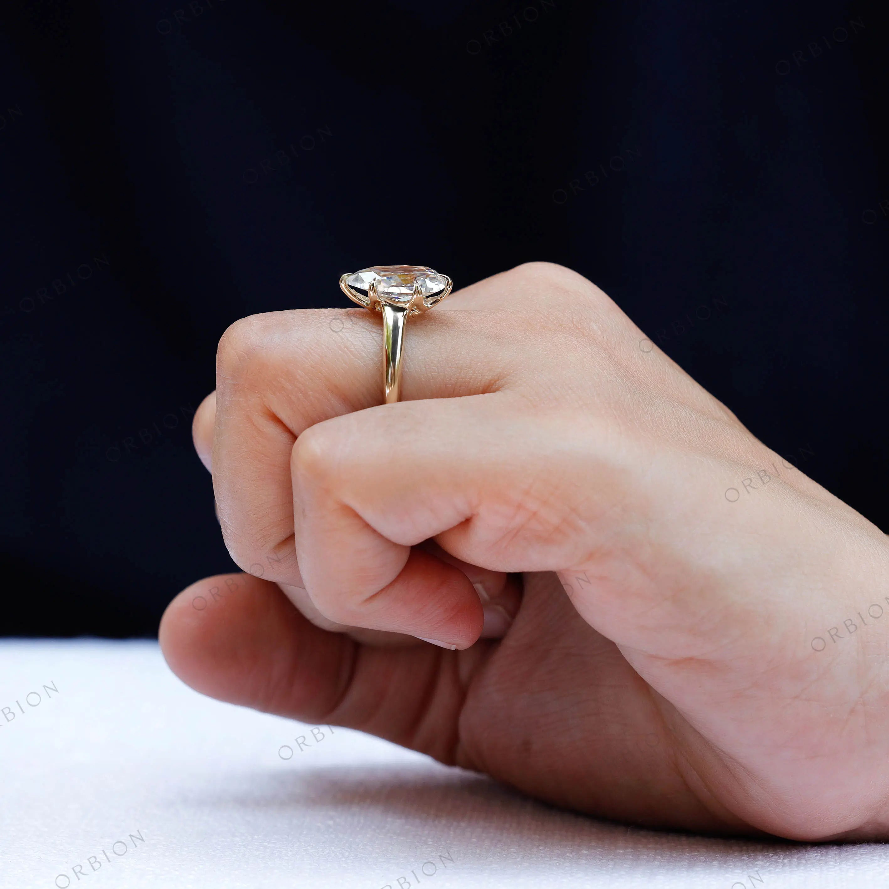 Elegant pear shape moissanite ring on hand yellow gold band