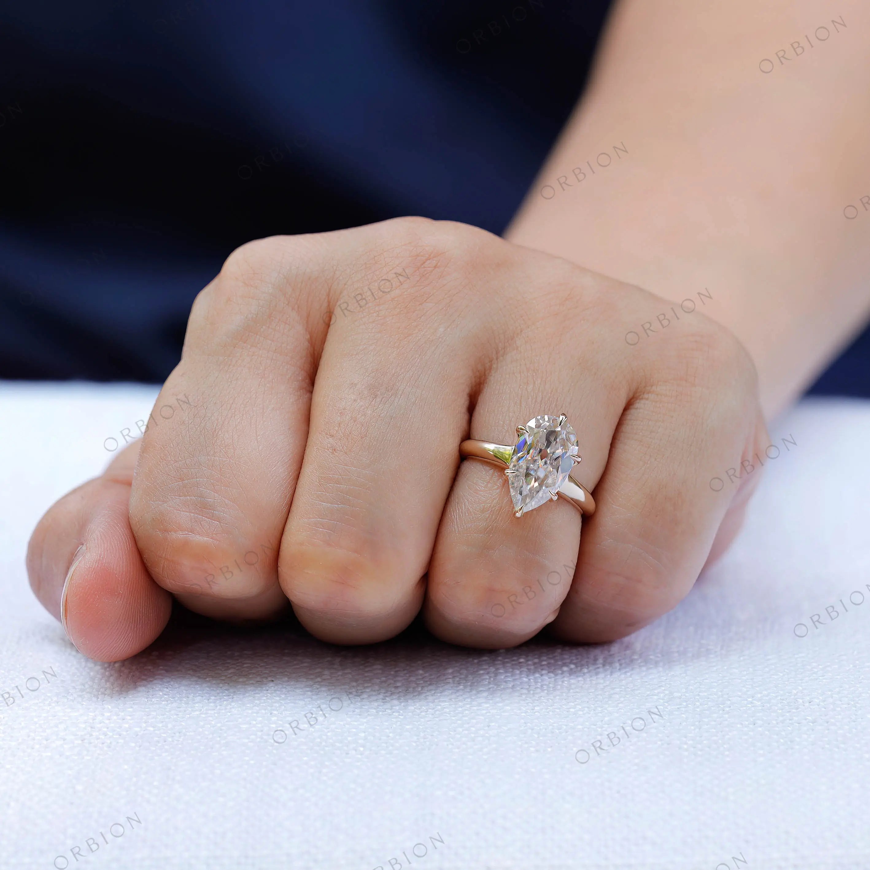 Classic solitaire pear moissanite ring worn on hand minimal gold band