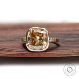 Front view close-up of cushion-shaped Moissanite in yellow gold bezel setting.