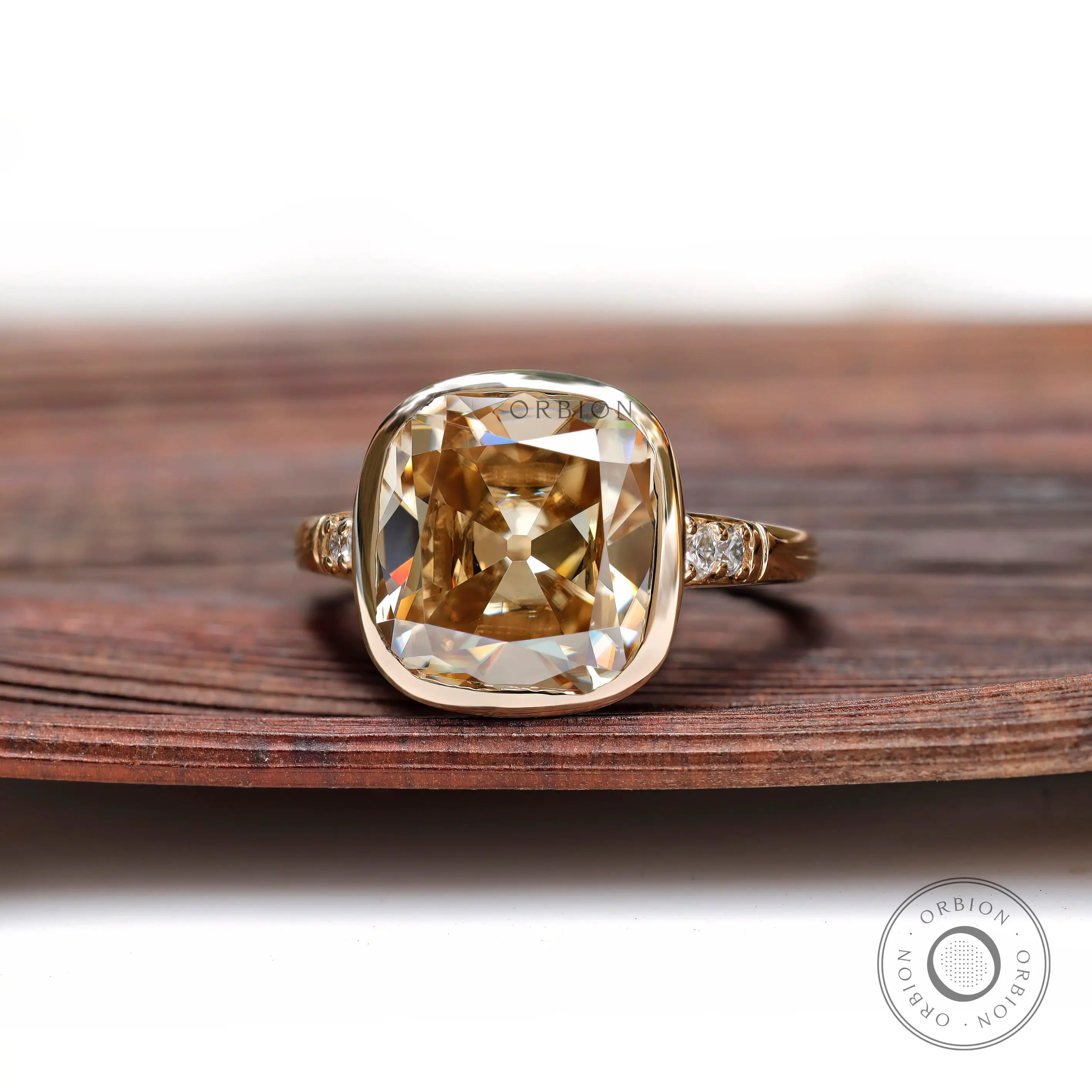 Front view close-up of cushion-shaped Moissanite in yellow gold bezel setting.
