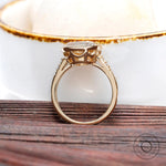 Top view of elongated cushion Moissanite ring with side diamonds set in yellow gold.