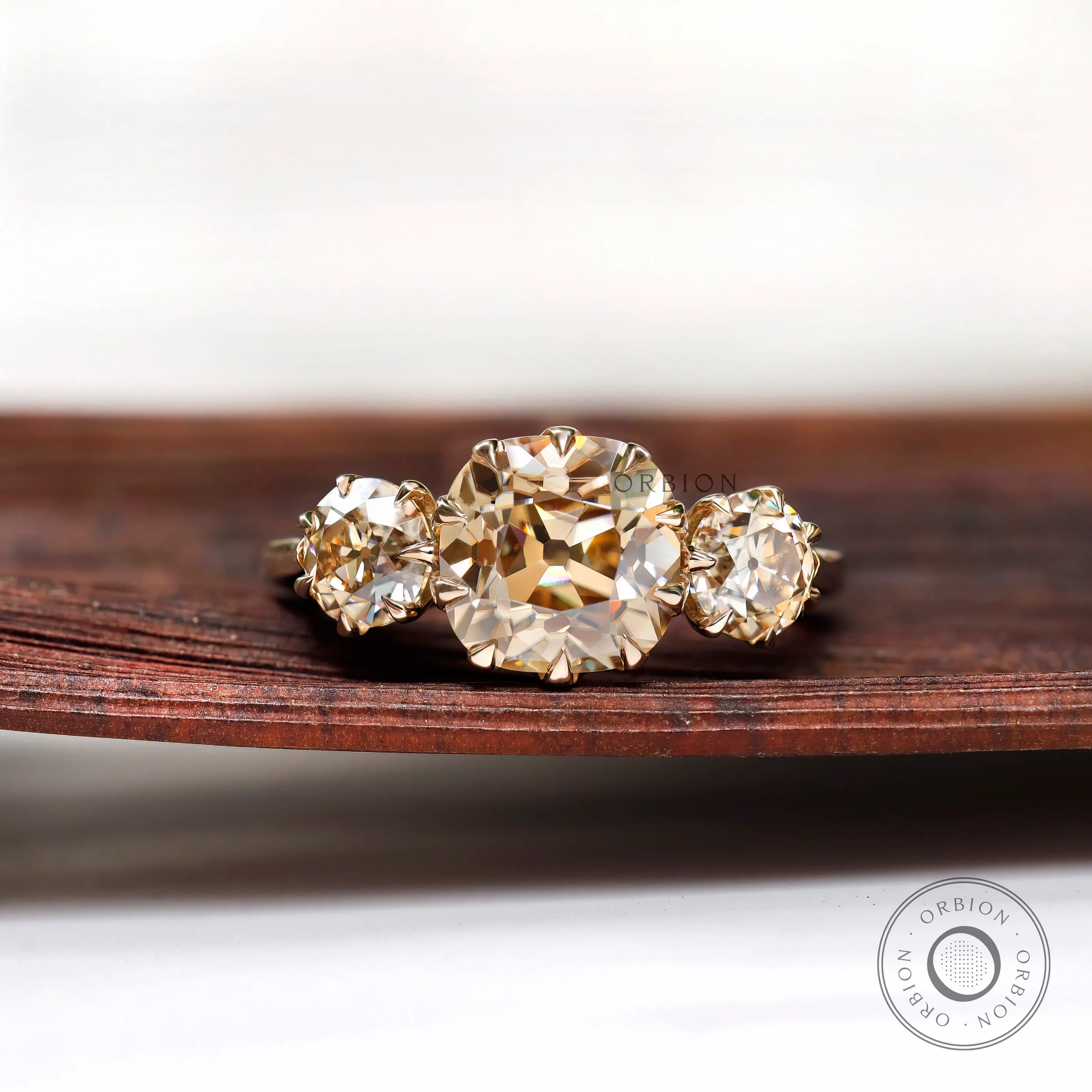 Light champagne three stone moissanite ring with cushion center top view