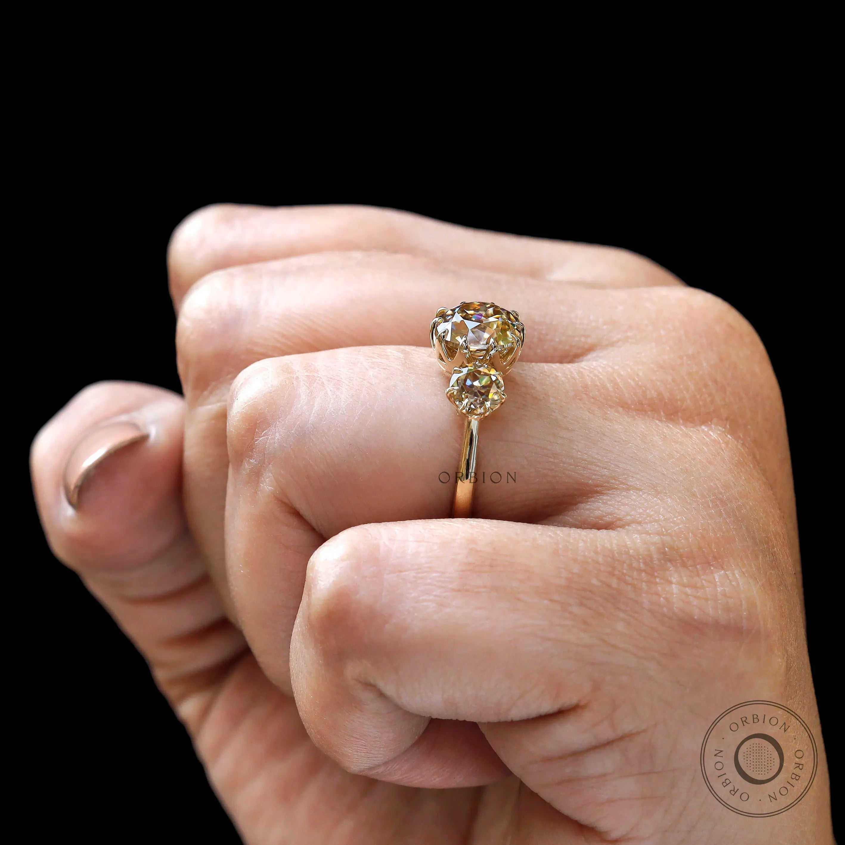 Hand worn three stone champagne moissanite ring side view