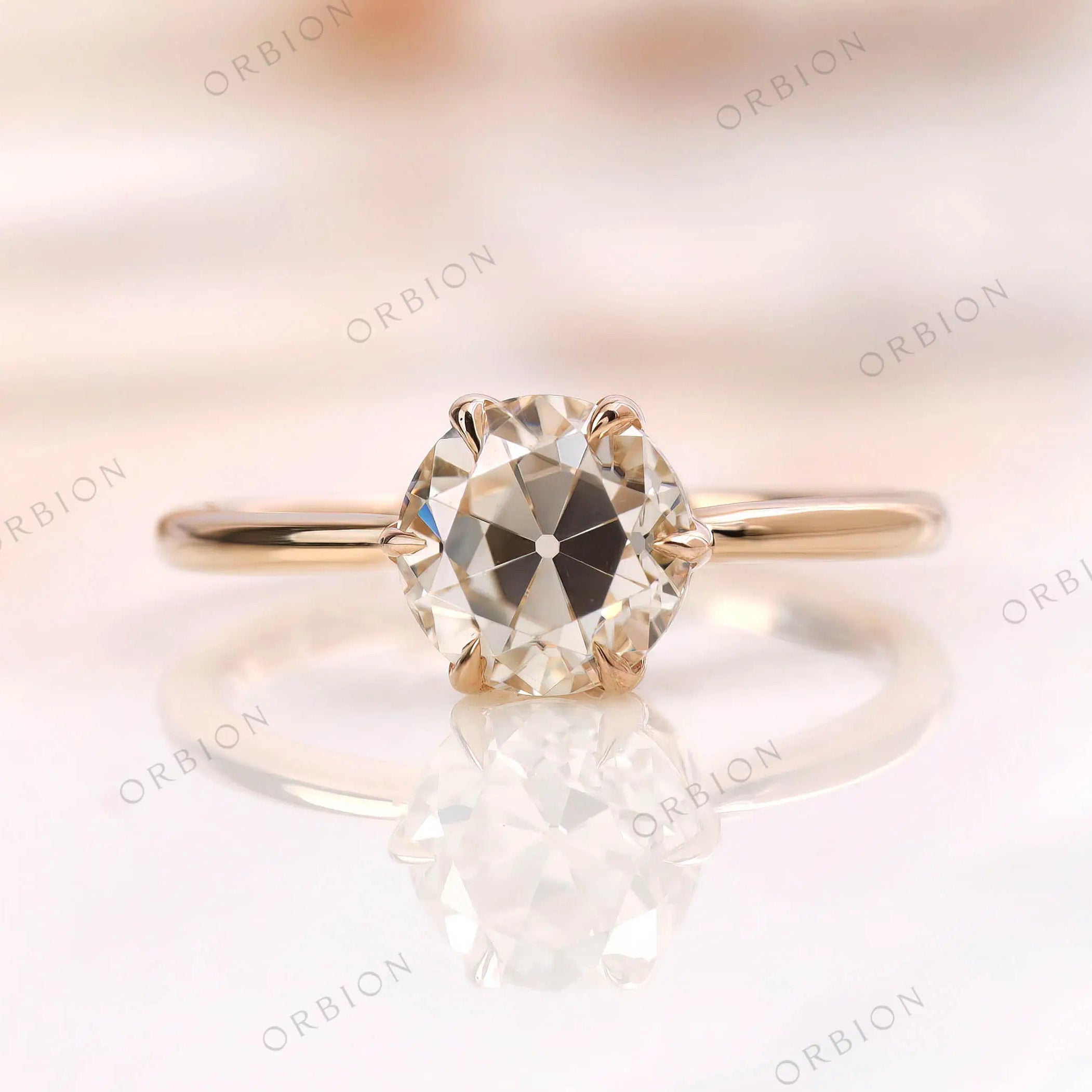 Solitaire moissanite engagement ring with round Old European cut center stone in 10K yellow gold.
