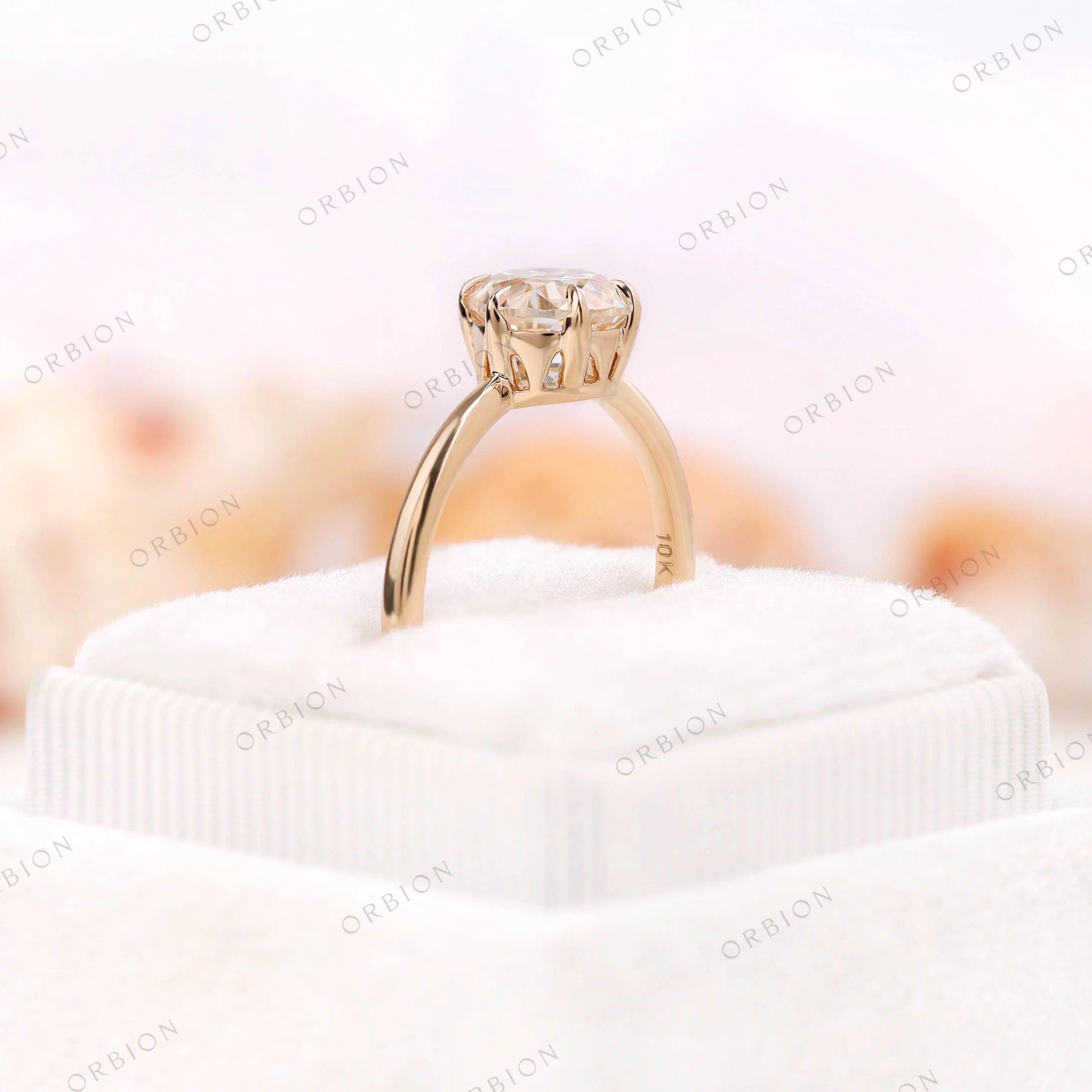Ring placed on a velvet ring box showing the 1.50 CT round moissanite in 10K yellow gold.