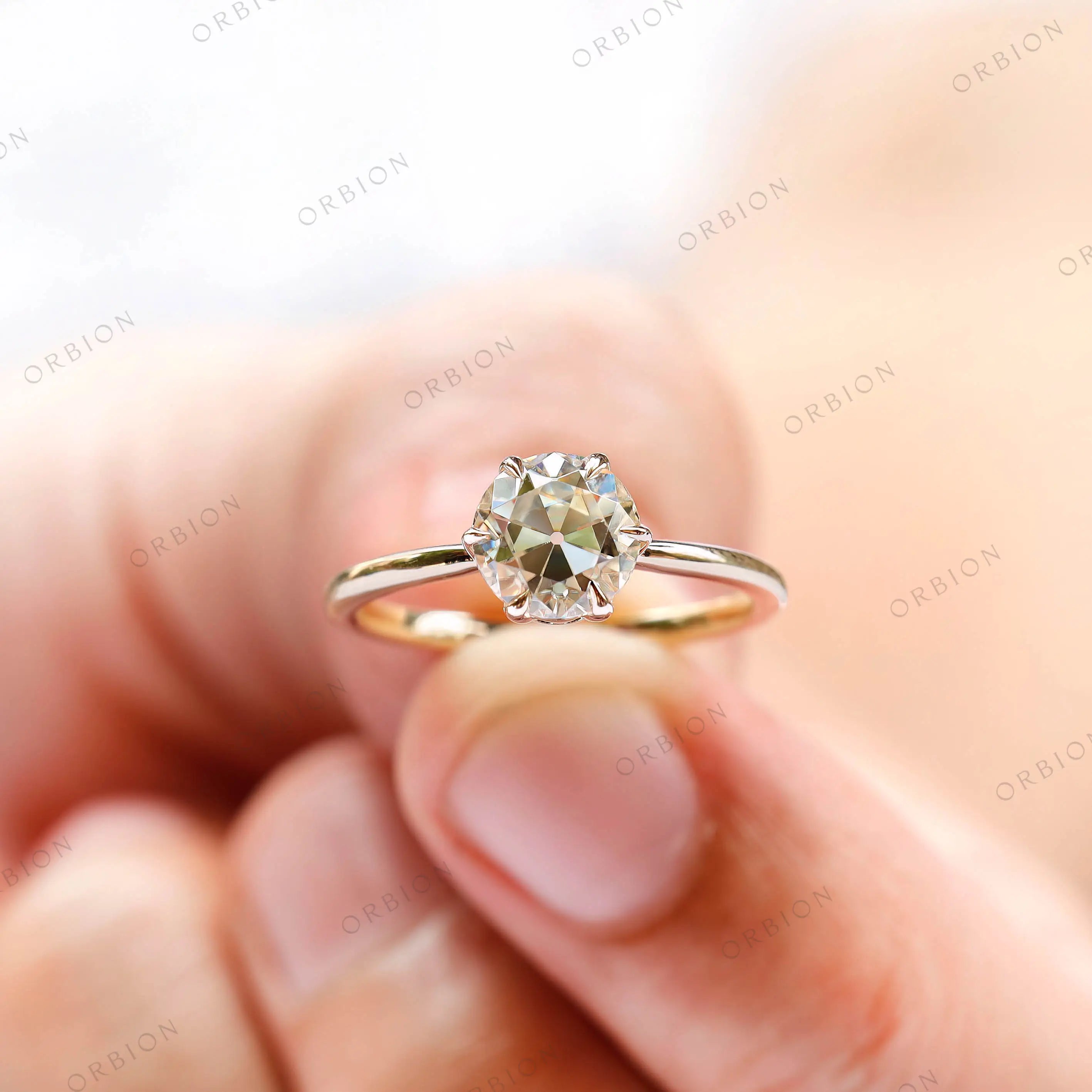 Close-up of round moissanite solitaire engagement ring in 10K yellow gold, being held for a perfect display.