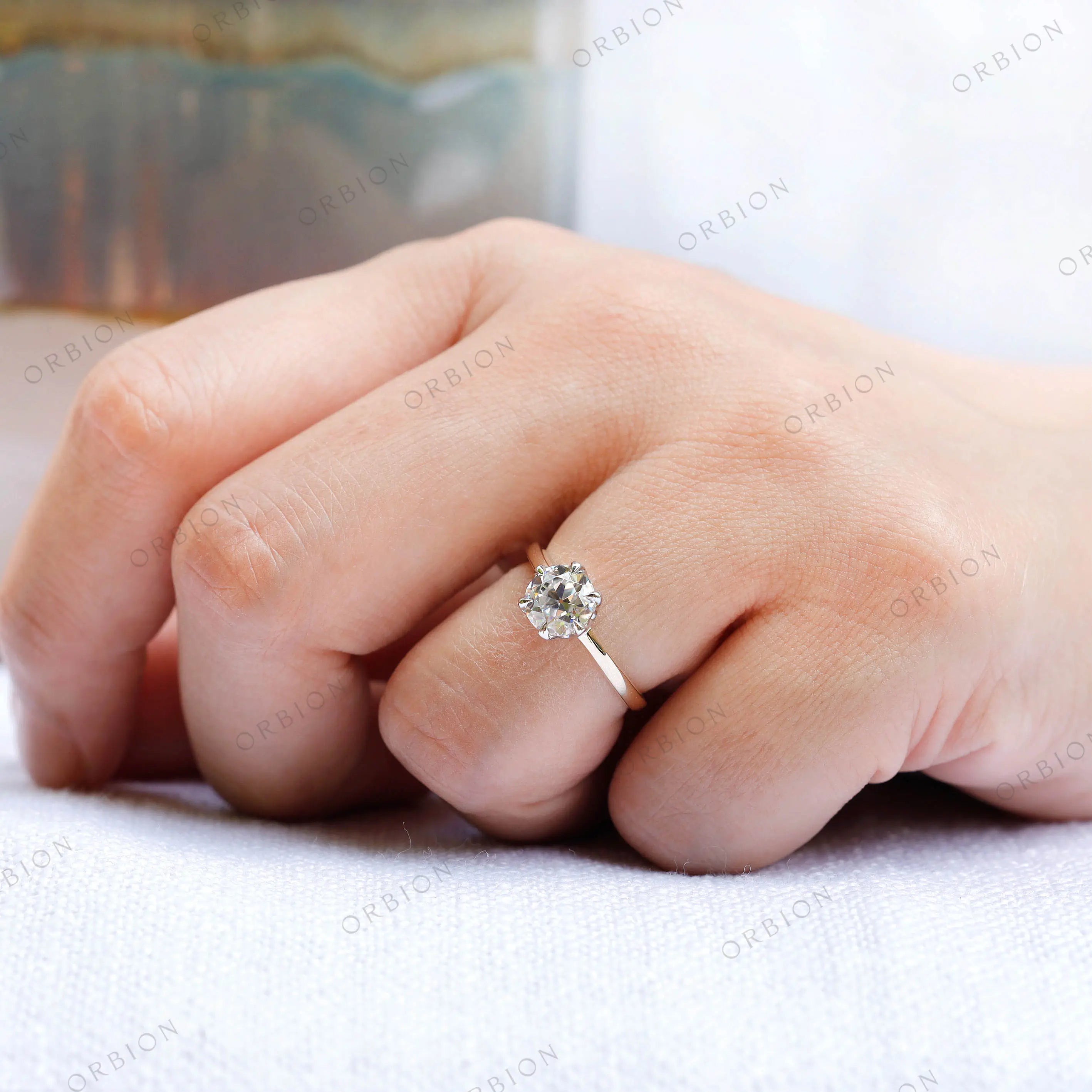 Close-up shot of the ring on a finger, showcasing the elegant bezel setting and the dual-tone 10K gold band.