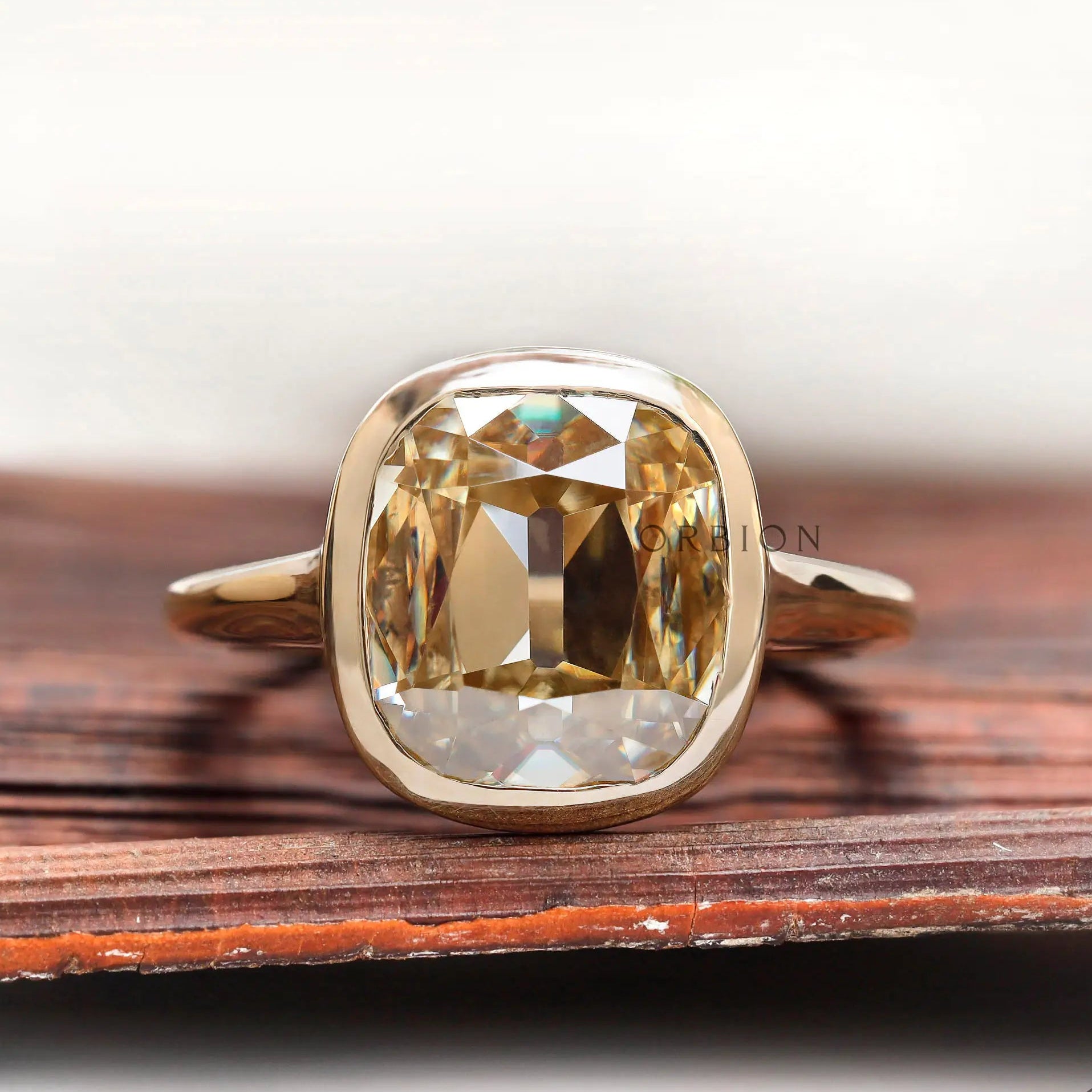 Front view of elongated cushion champagne moissanite bezel engagement ring
