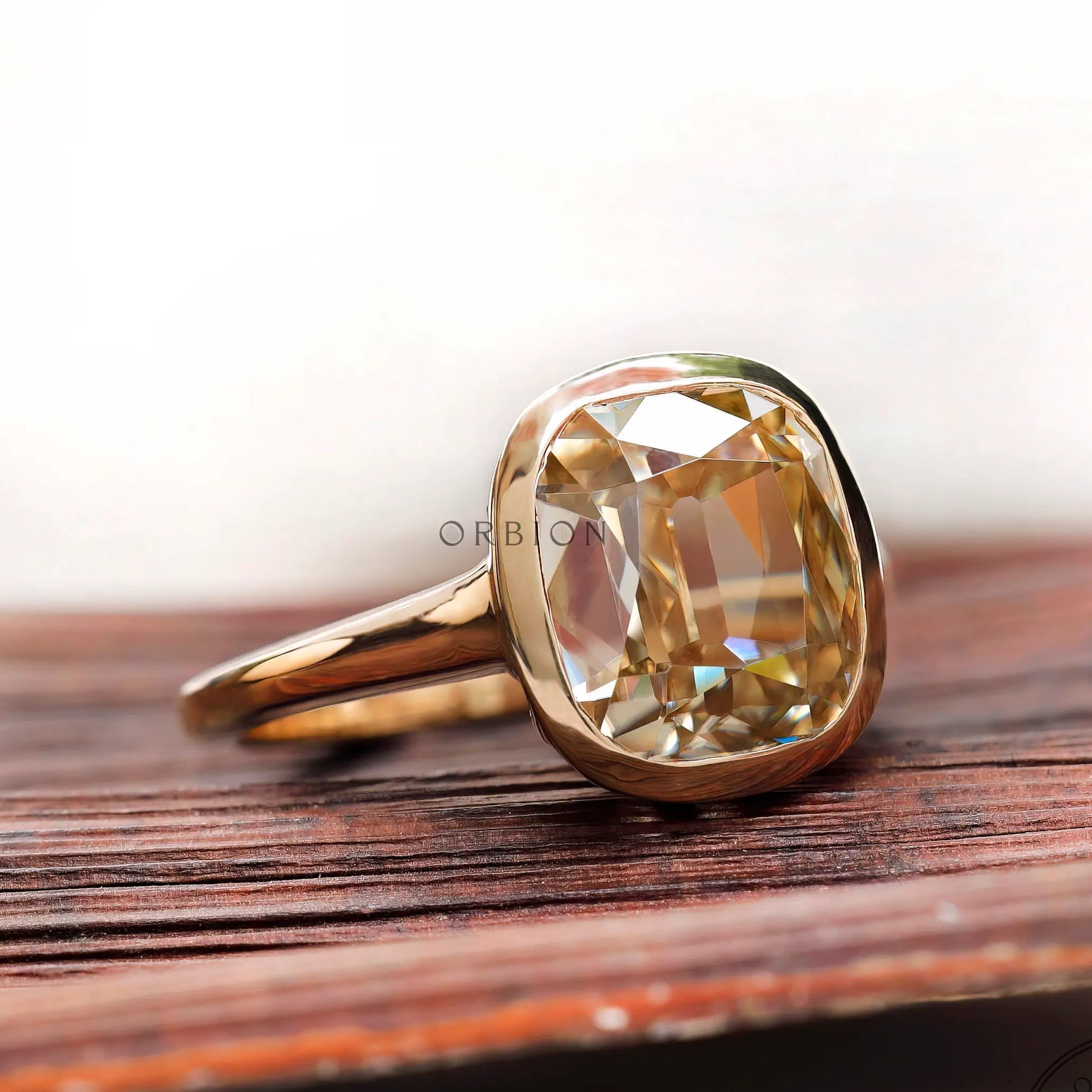 Elongated cushion light champagne moissanite bezel solitaire ring in yellow gold