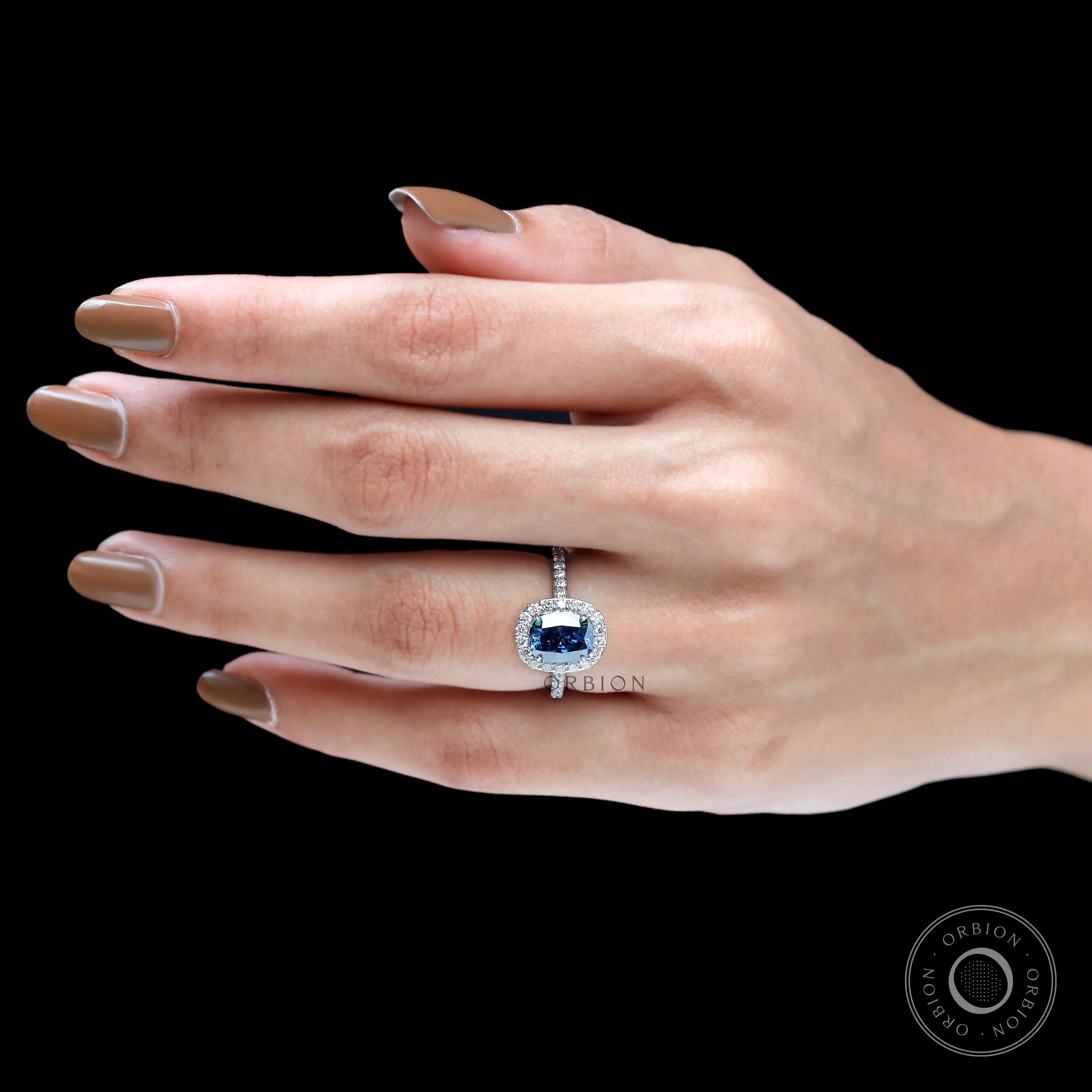Cushion cut blue stone halo ring on fingure 