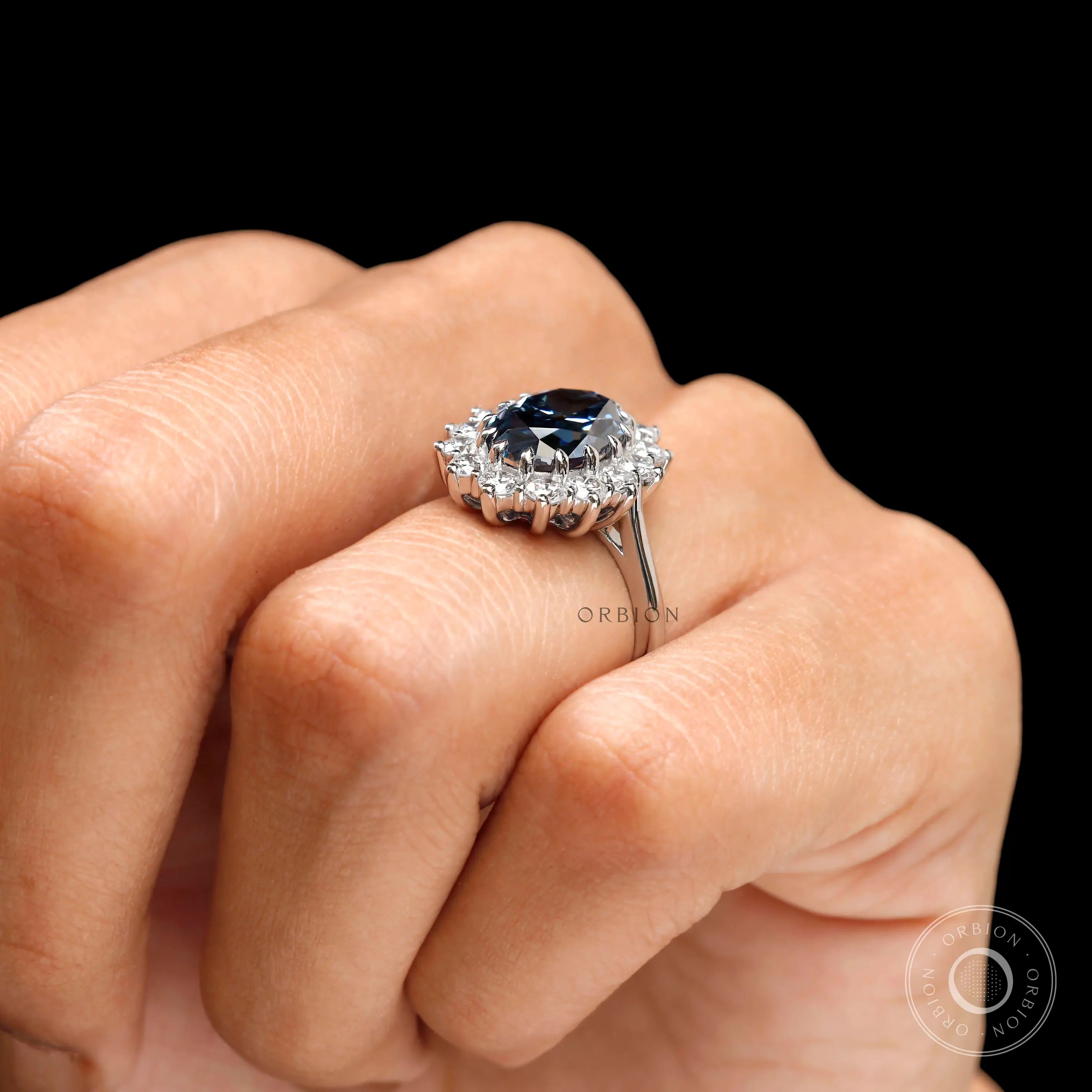 Oval deep blue moissanite halo engagement ring on hand