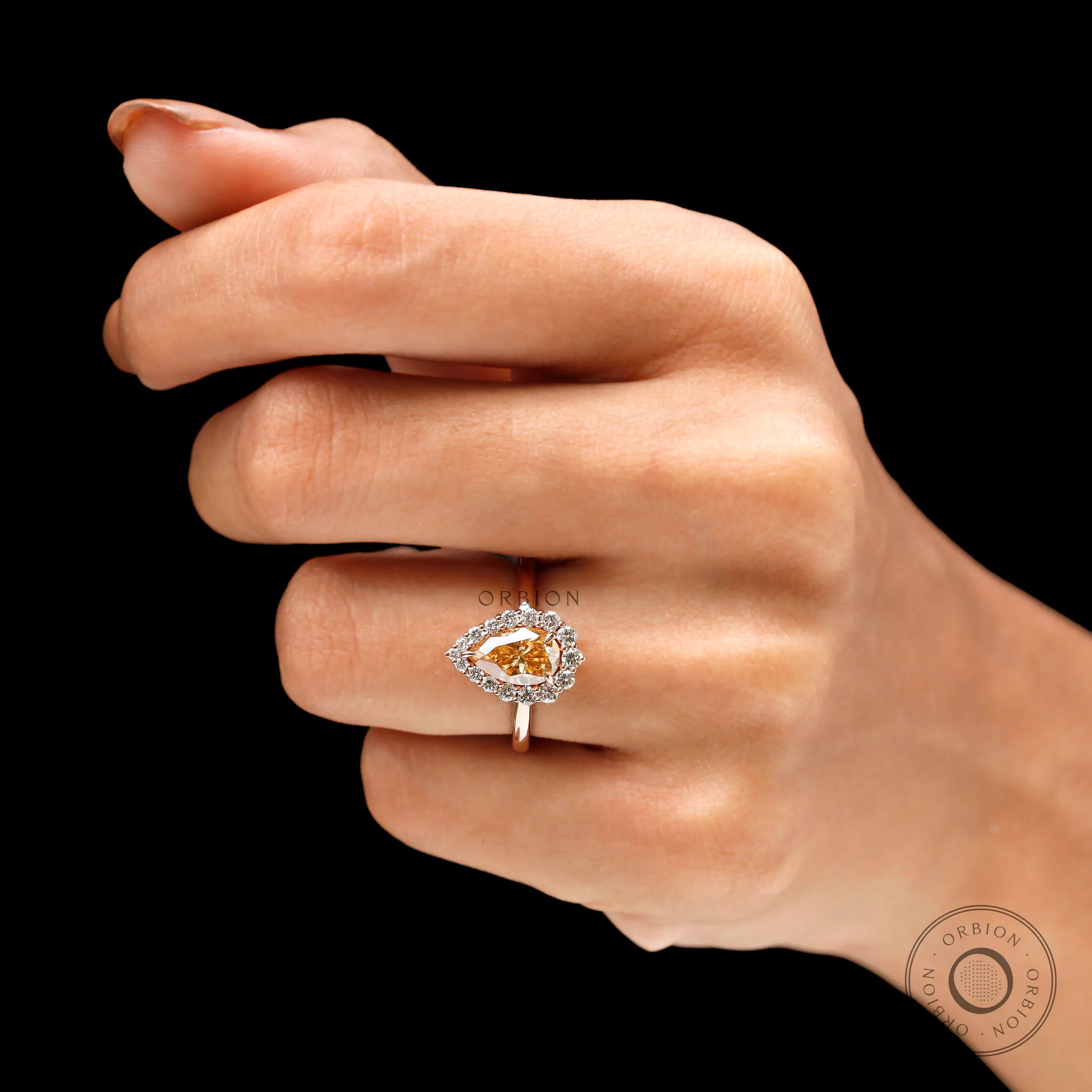 Halo engagement ring with pear shaped center stone on fingure