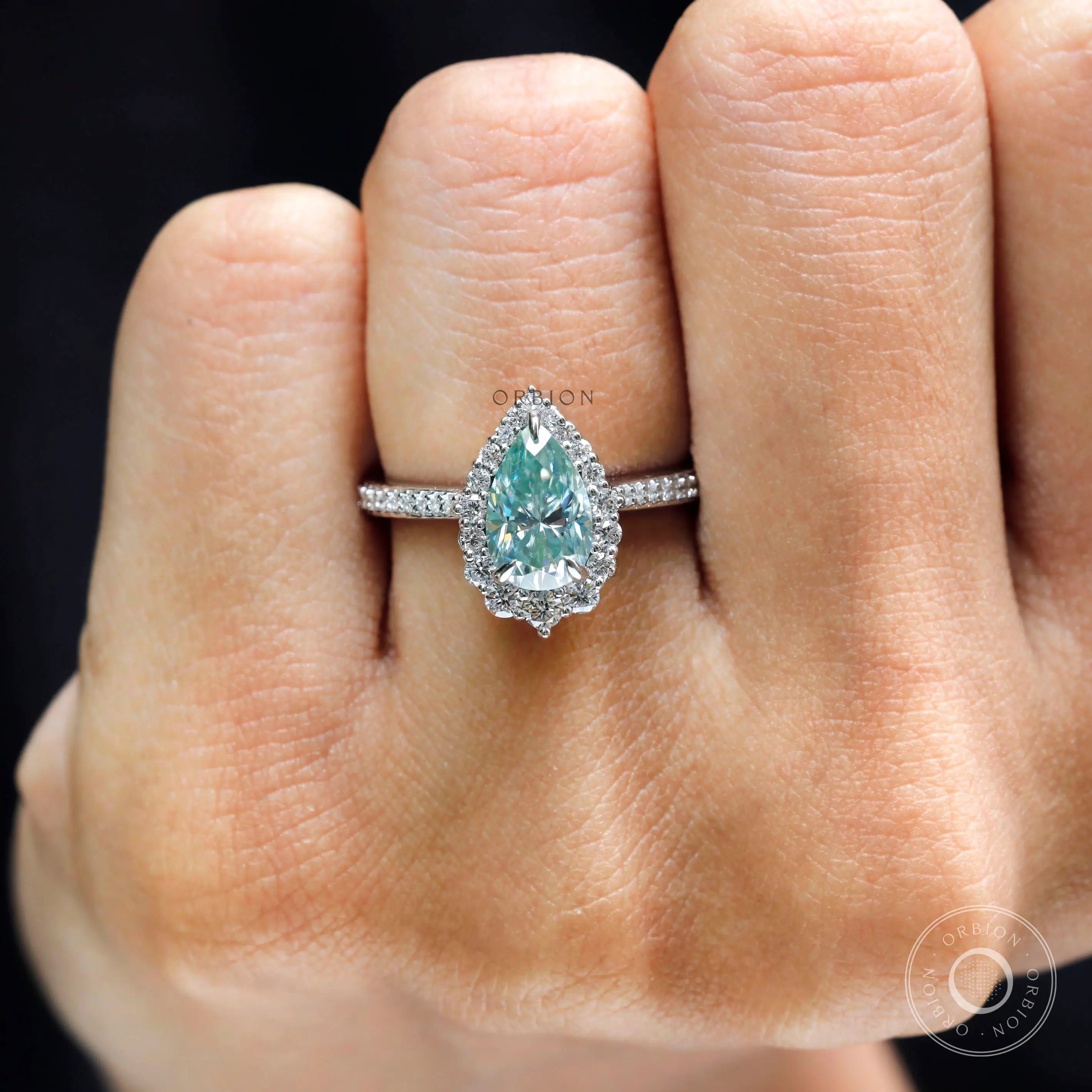 Close up of pear light green moissanite halo setting