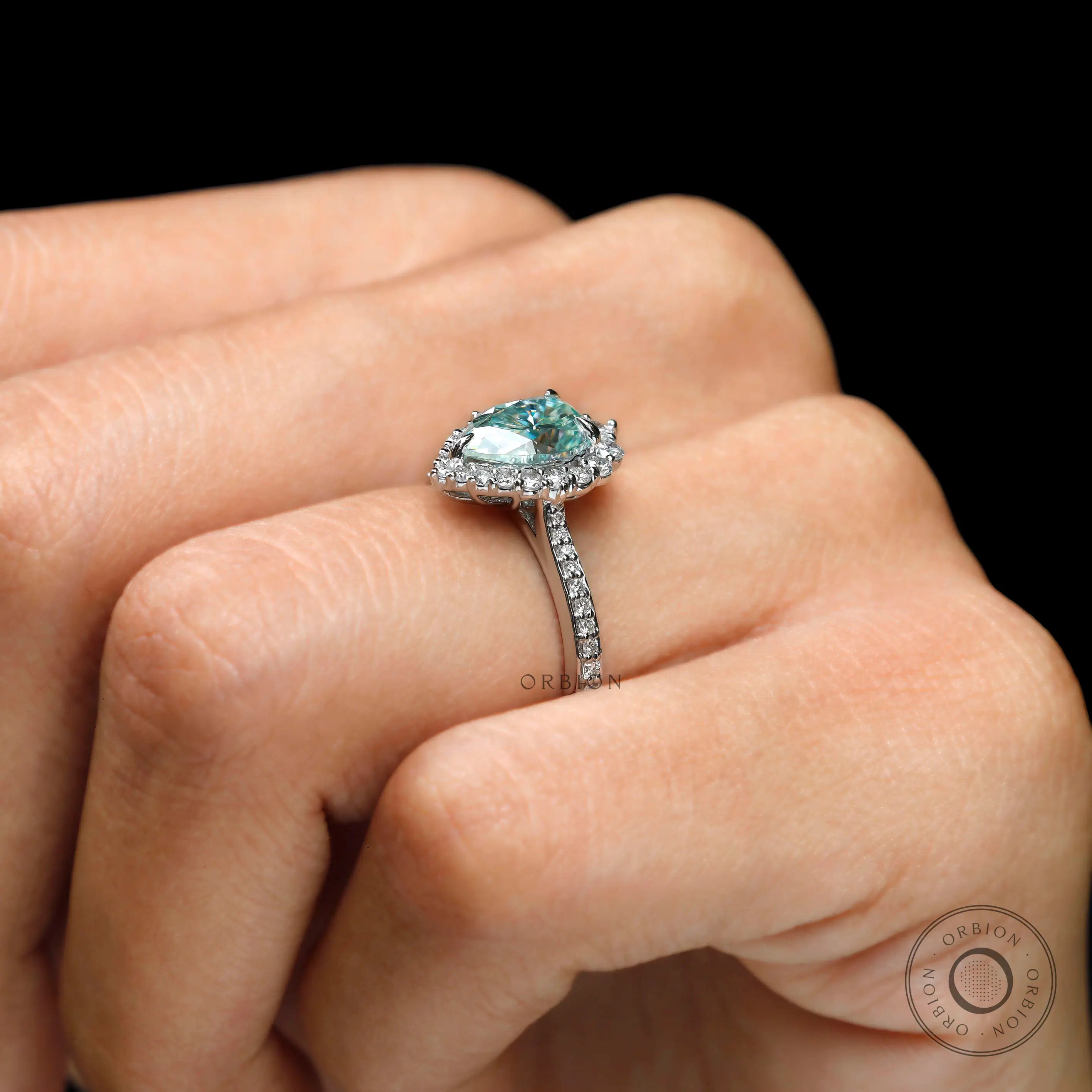 Elegant pear halo light green moissanite ring on hand