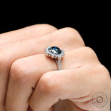 White gold halo engagement ring with dark grey center stone on fingure
