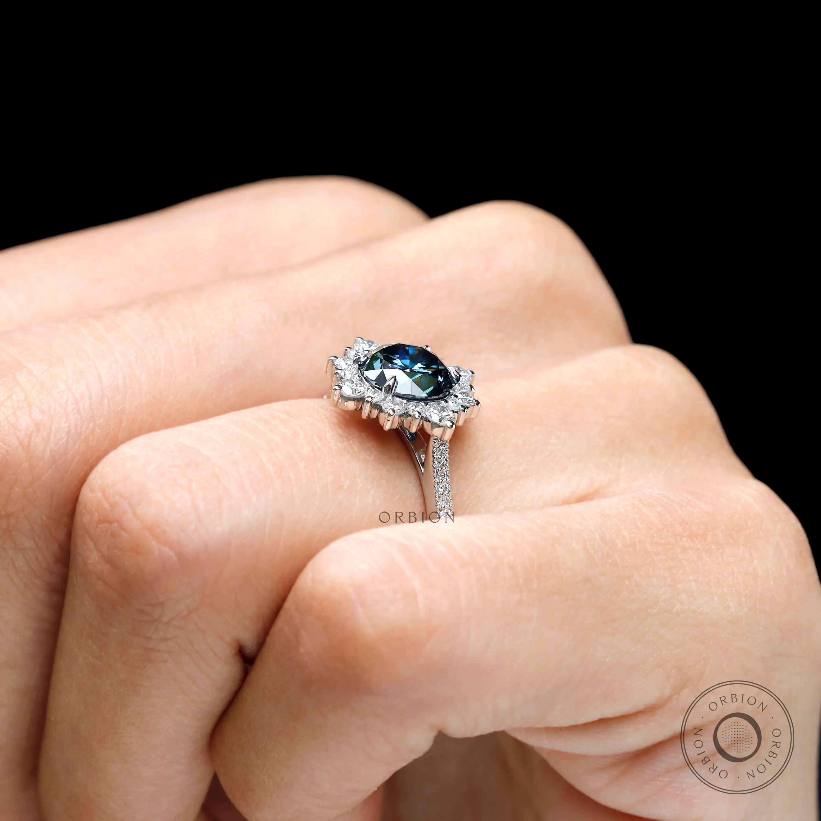 White gold halo engagement ring with dark grey center stone on fingure