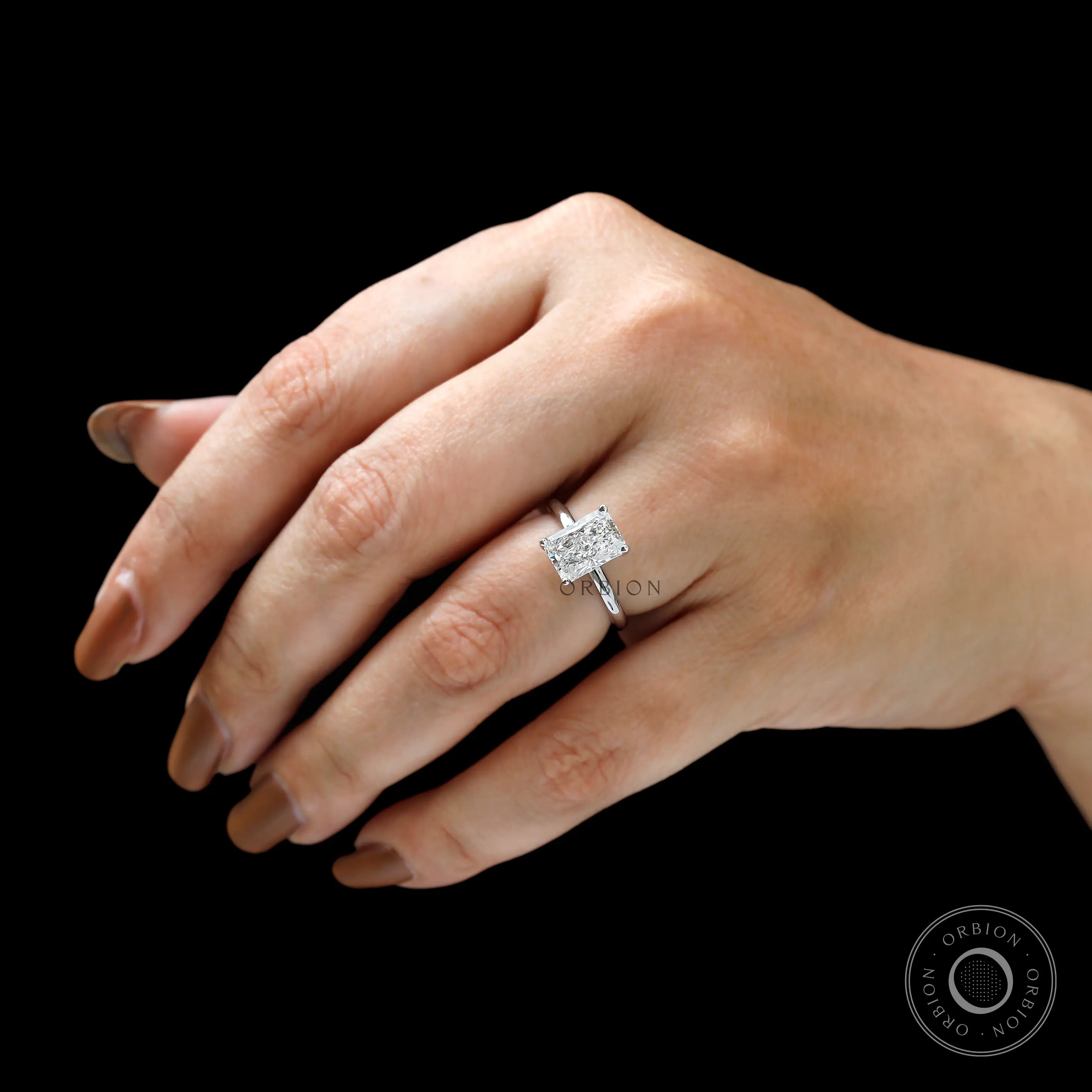 Radiant cut diamond ring worn on hand for scale