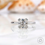 Asscher cut Moissanite solitaire ring on a white marble surface.