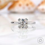 Asscher cut Moissanite solitaire ring on a white marble surface.