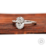 Front view of oval diamond solitaire ring on wooden surface