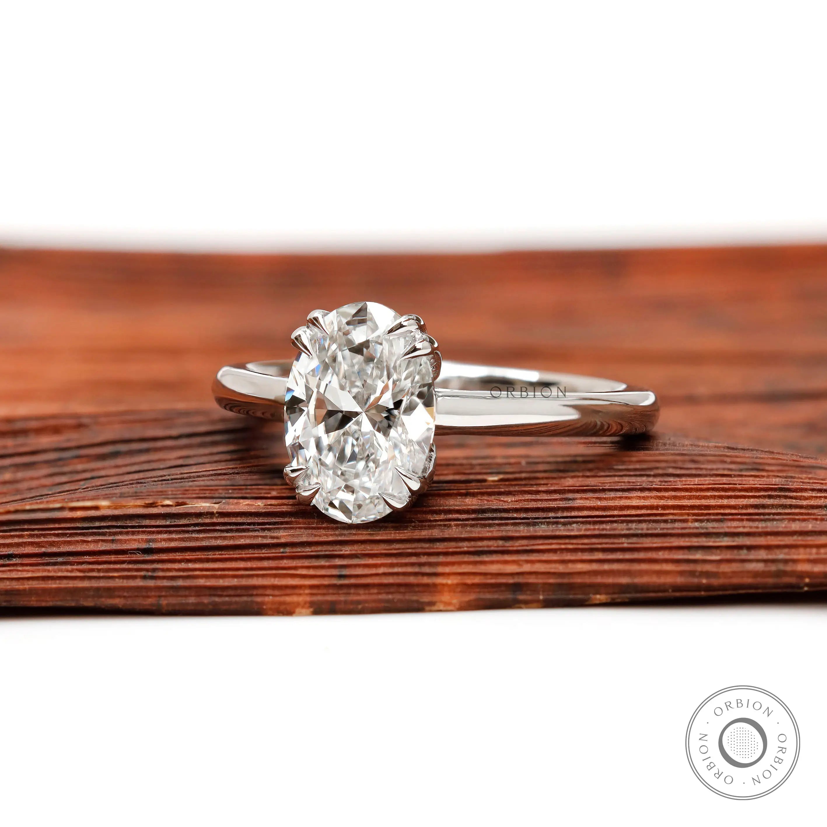 Front view of oval diamond solitaire ring on wooden surface
