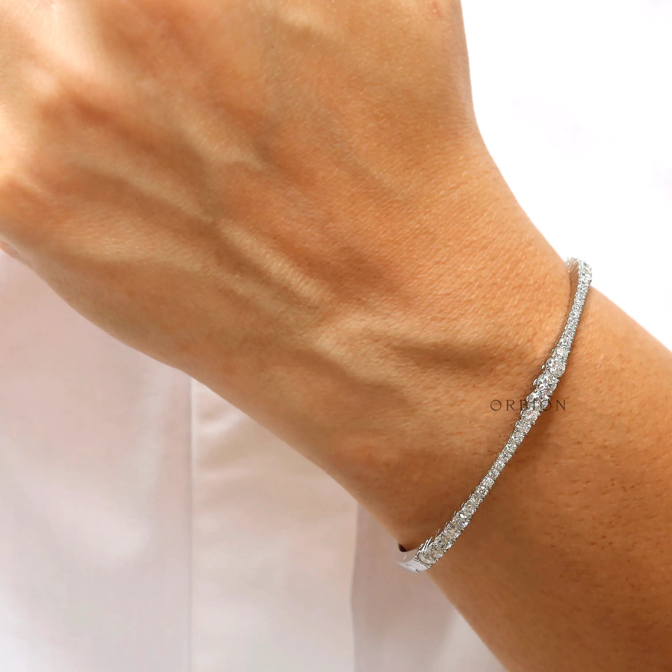 Close up of graduating lab grown diamonds set in solid gold bangle