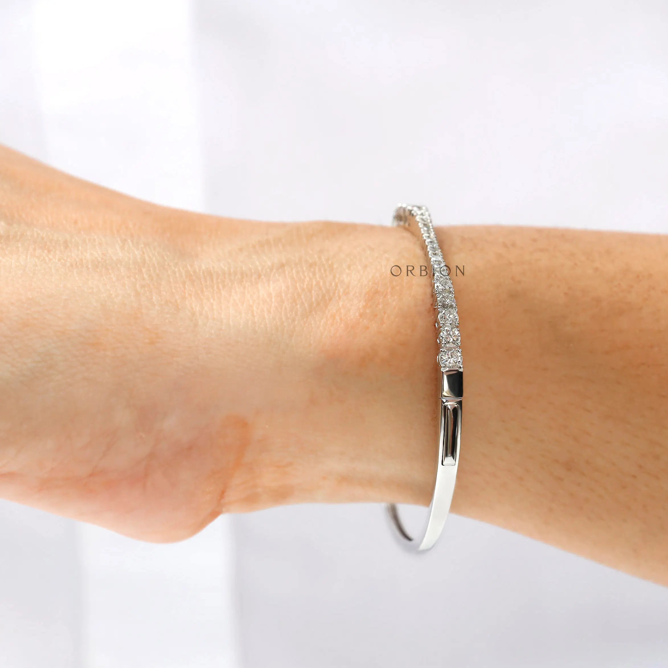 Graduating diamond bangle bracelet worn on wrist for size reference