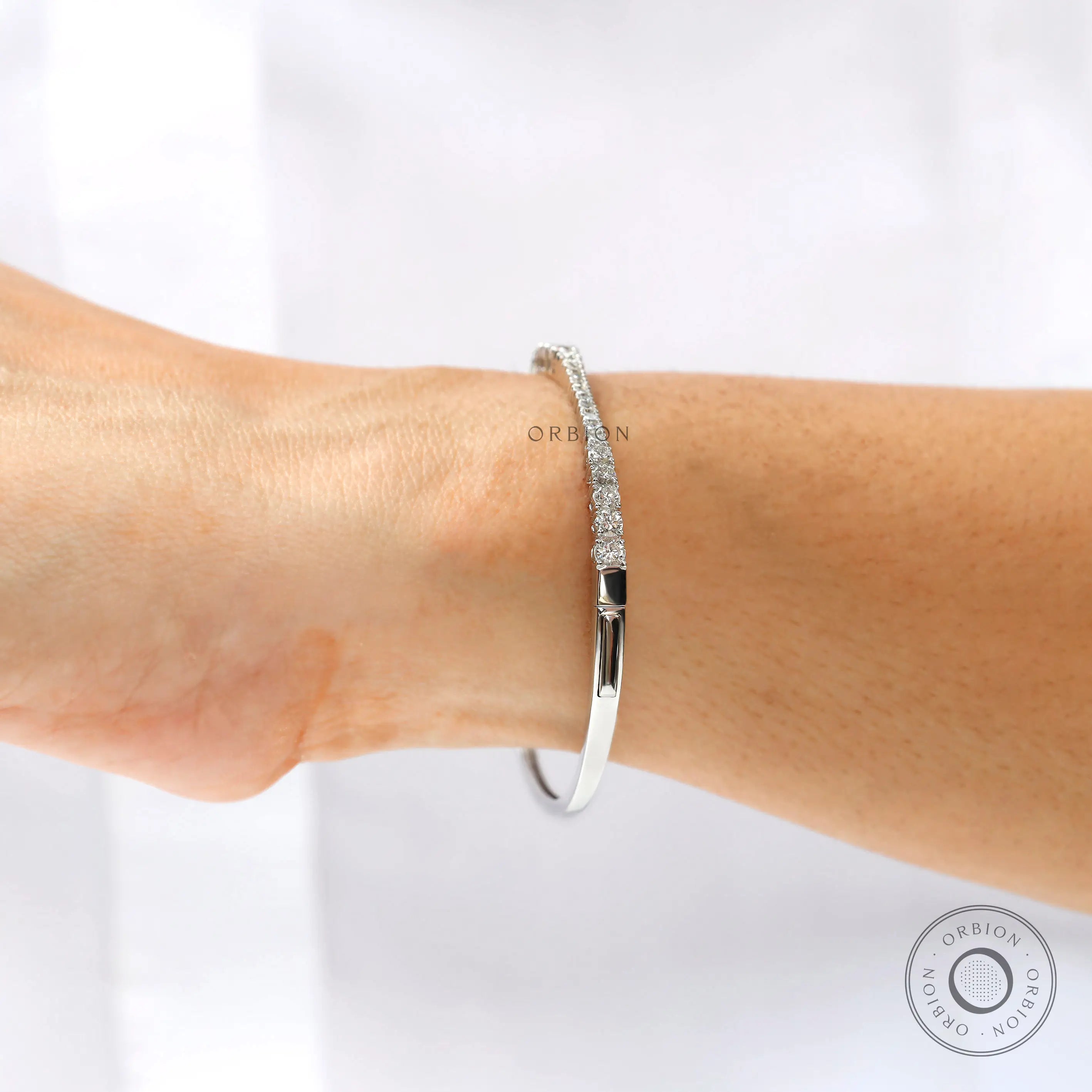 Graduating diamond bangle bracelet worn on wrist for size reference