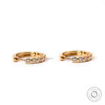 Yellow gold huggie hoop earrings with 2mm round lab diamonds close up