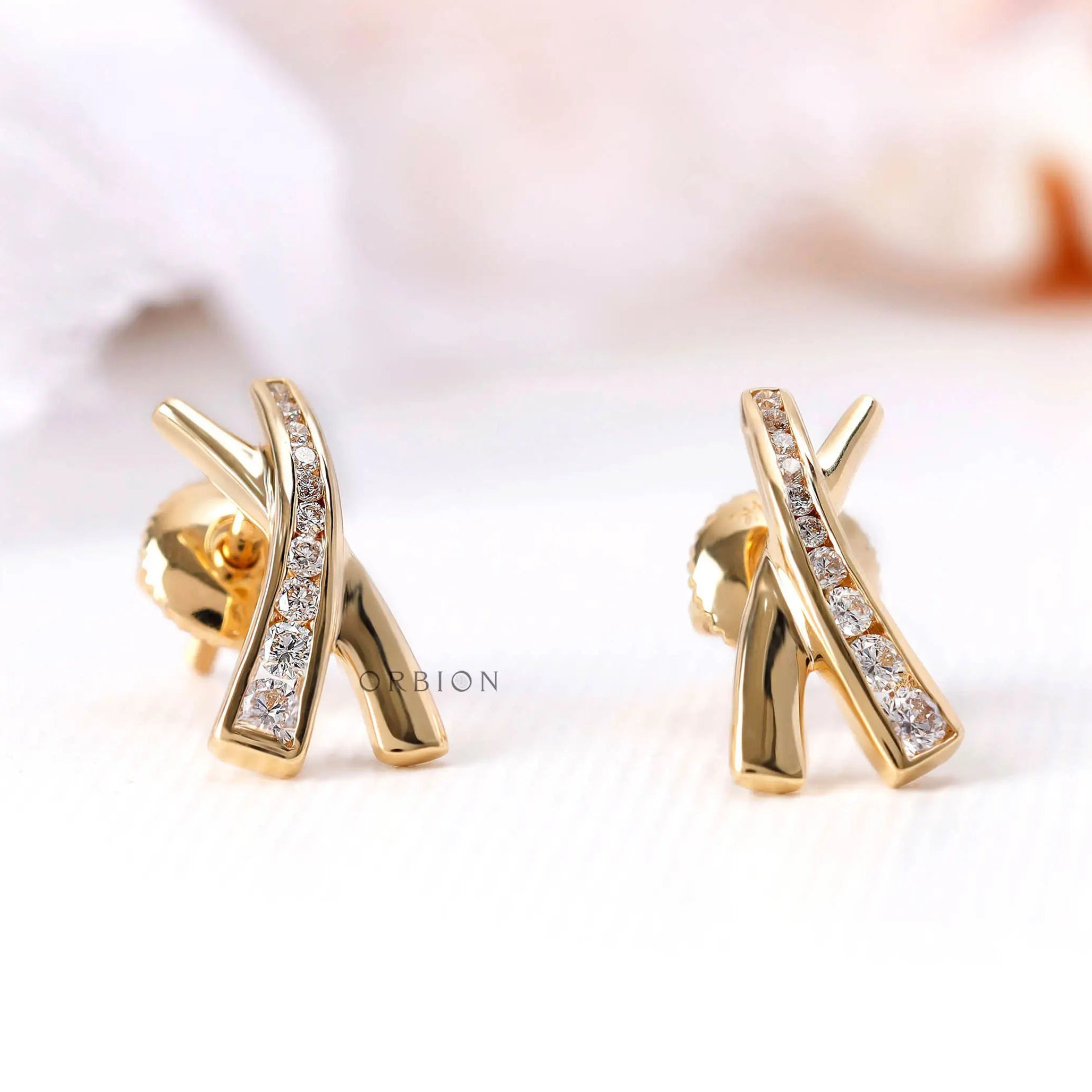 Yellow gold X shape diamond earrings close up detail