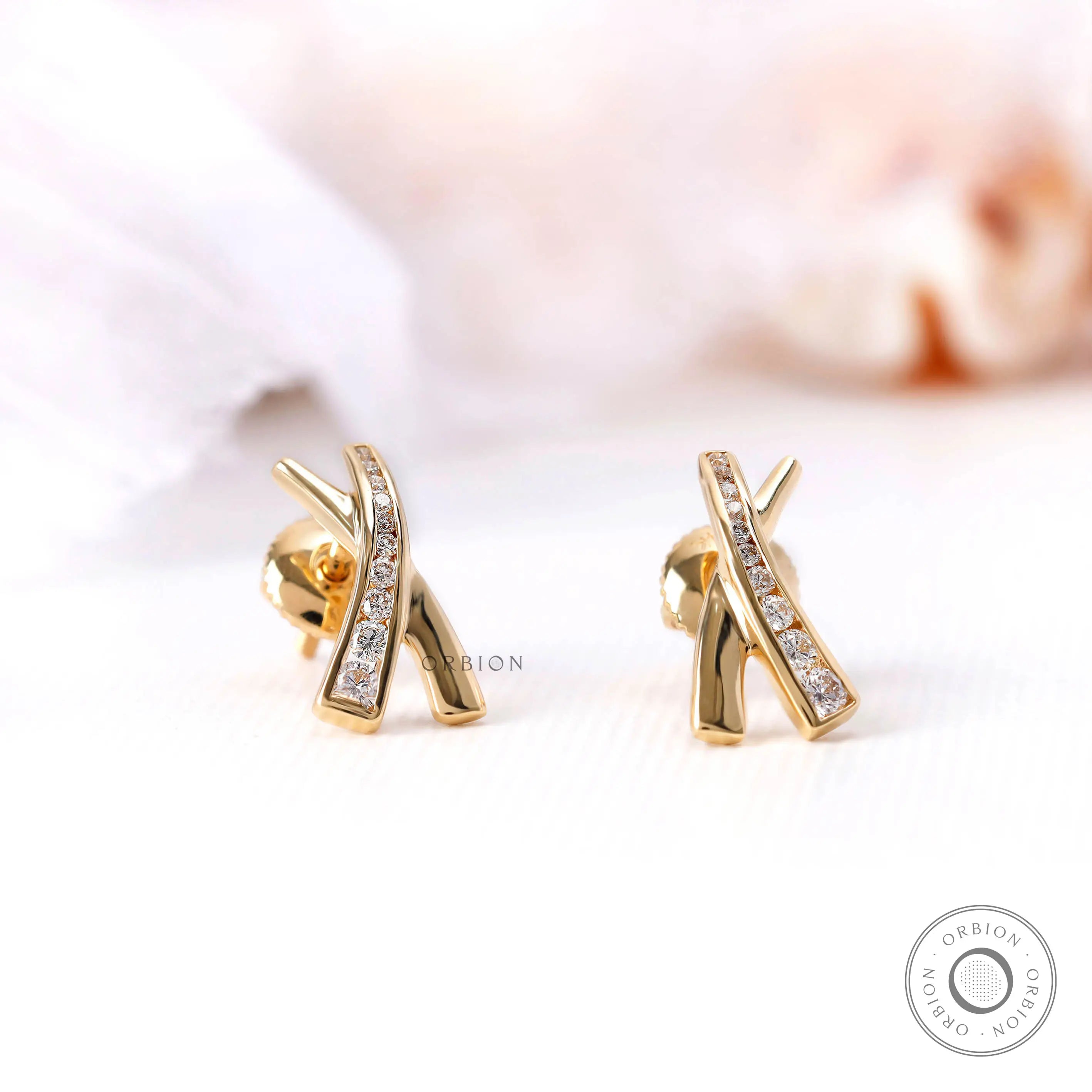 Yellow gold X shape diamond earrings close up detail