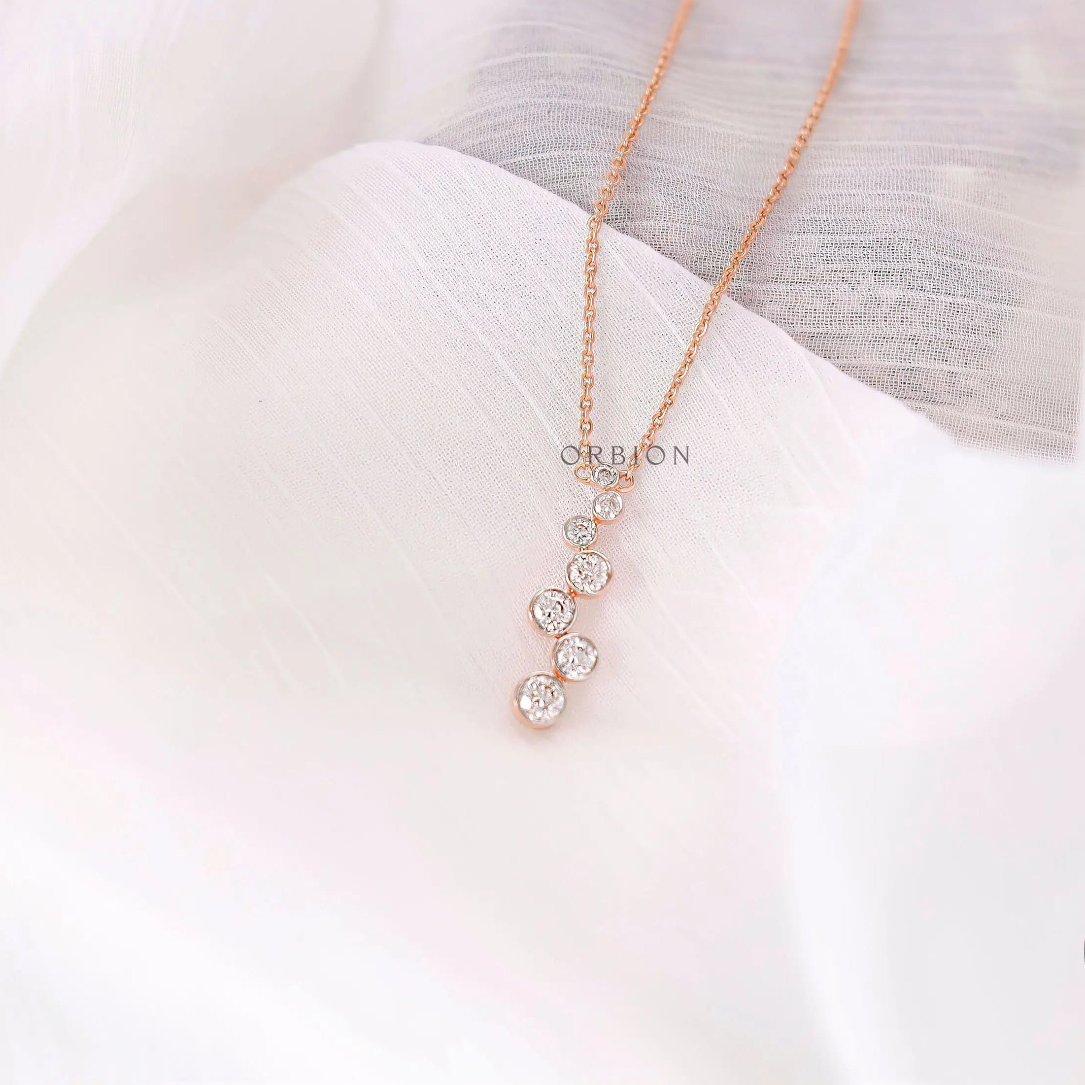Close-up of bezel set round lab diamonds in vertical drop pendant design