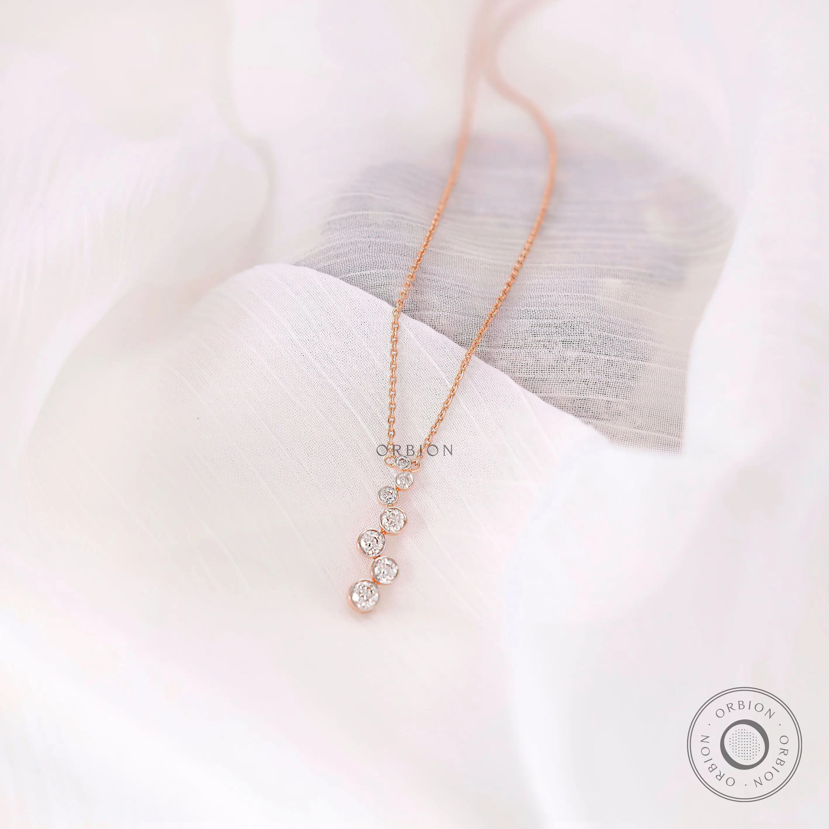 Close-up of bezel set round lab diamonds in vertical drop pendant design