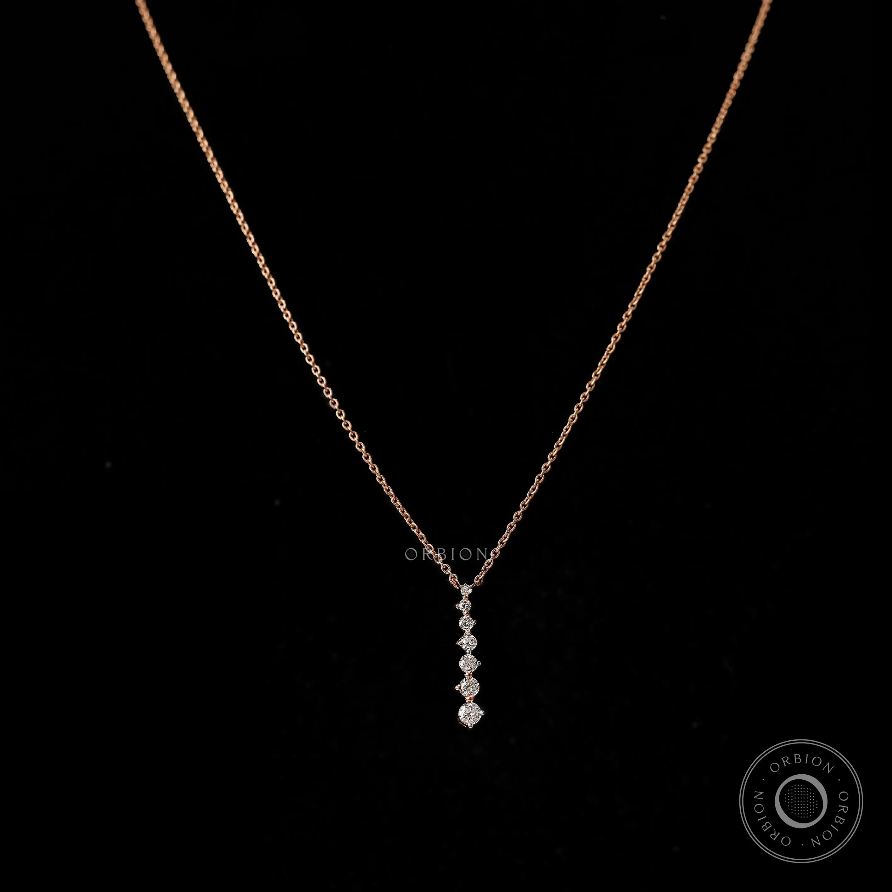 Dainty vertical graduating diamond pendant necklace in 14k rose gold, with a long drop design.